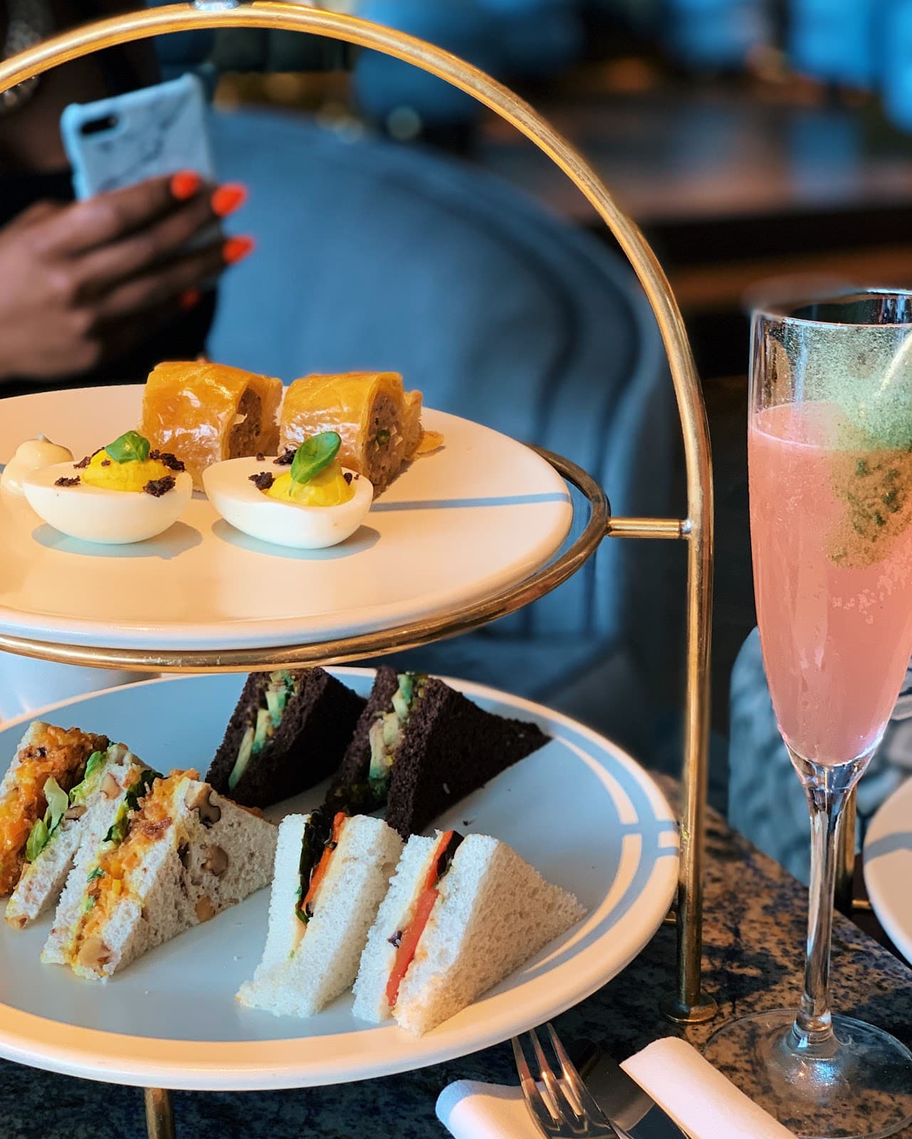 Two-tiered platter with assorted sandwiches and a pink cocktail in London