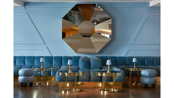 Elegant cocktail bar interior with blue seating and a large geometric mirror