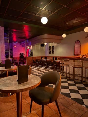 Stylish interior with checkered floor and modern seating in a cocktail bar in Toronto