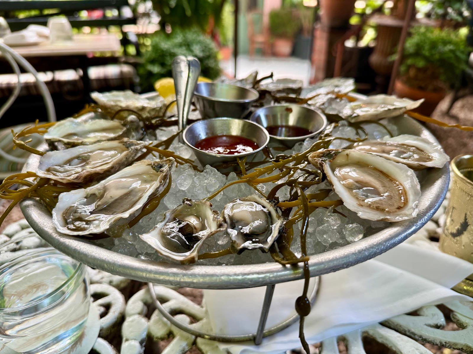 Plate of fresh oysters with sauce cups on ice at outdoor setting in New York