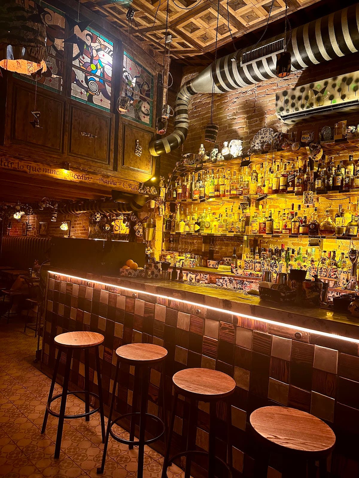 Cozy bar with illuminated shelves and rustic decor in premium cocktail bar in Barcelona