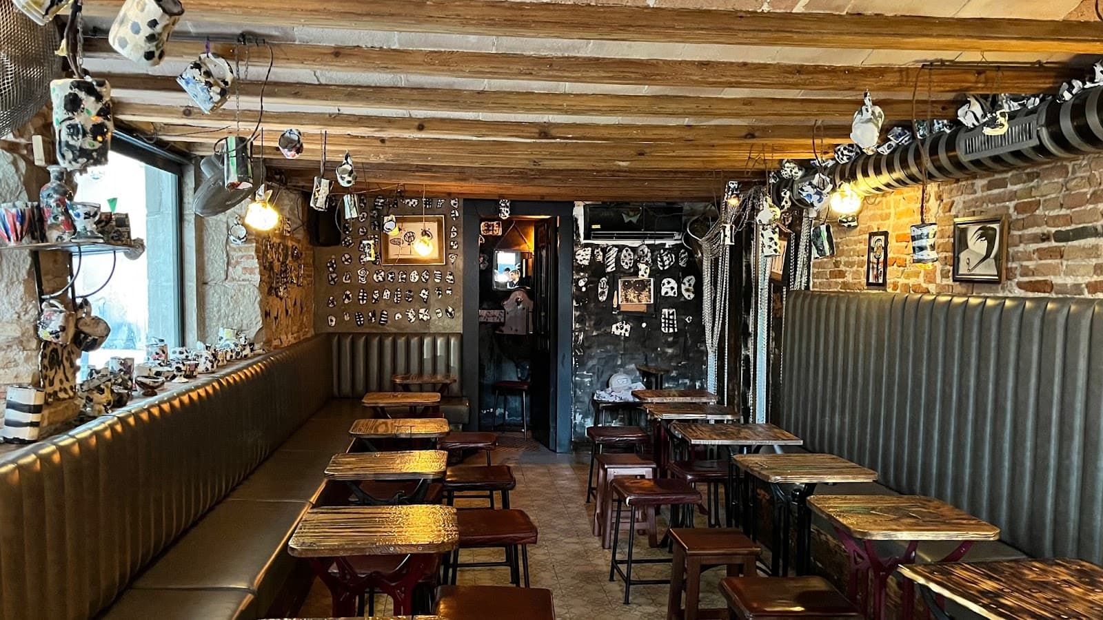 Cozy bar interior with wooden ceiling, decorated walls, and small tables in Barcelona