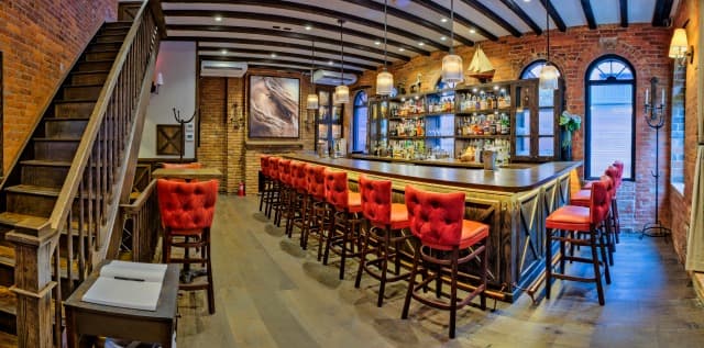 Spacious bar interior with red chairs and brick walls in New York