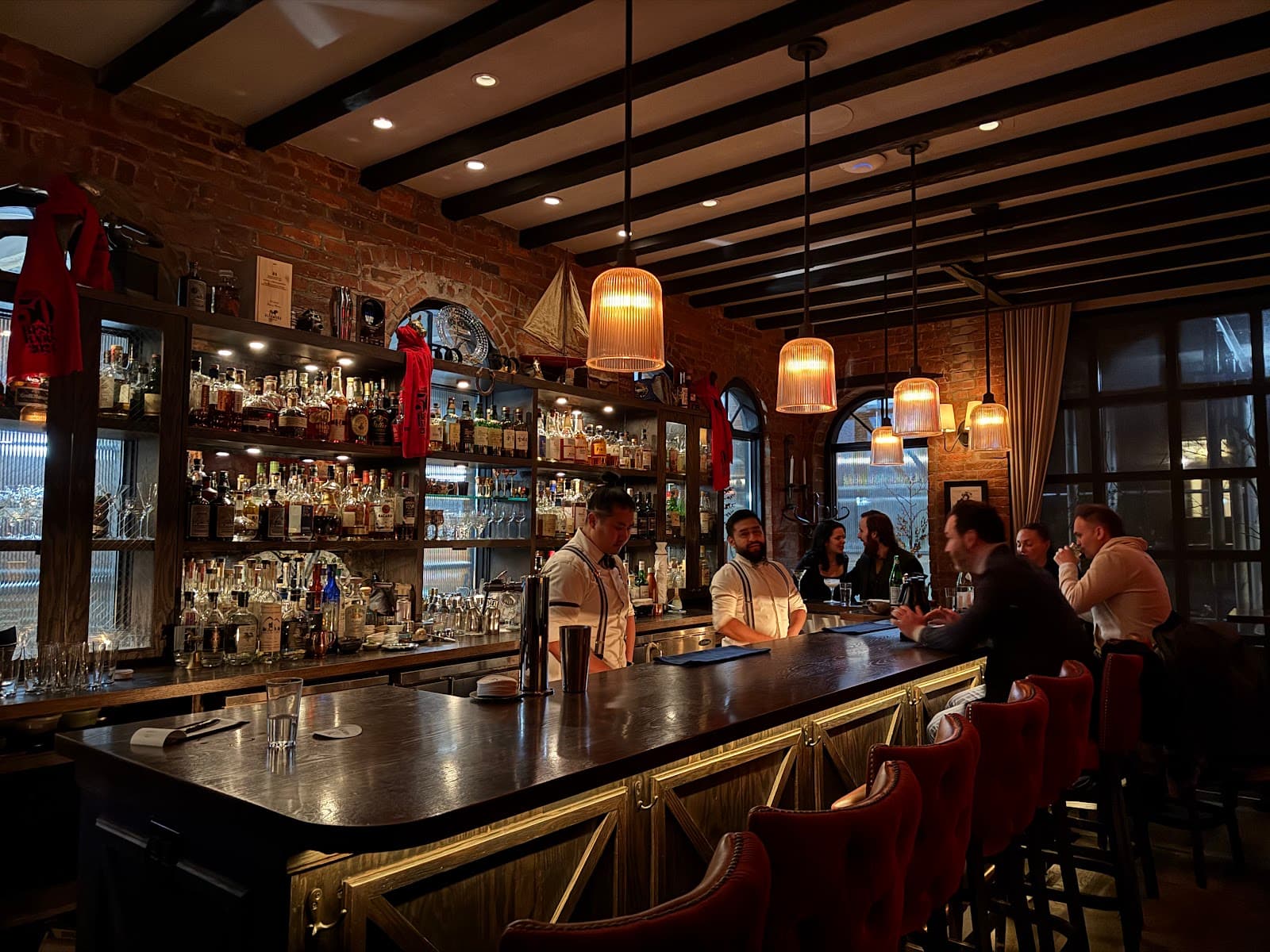Warm, inviting bar interior with exposed brick and patrons enjoying drinks
