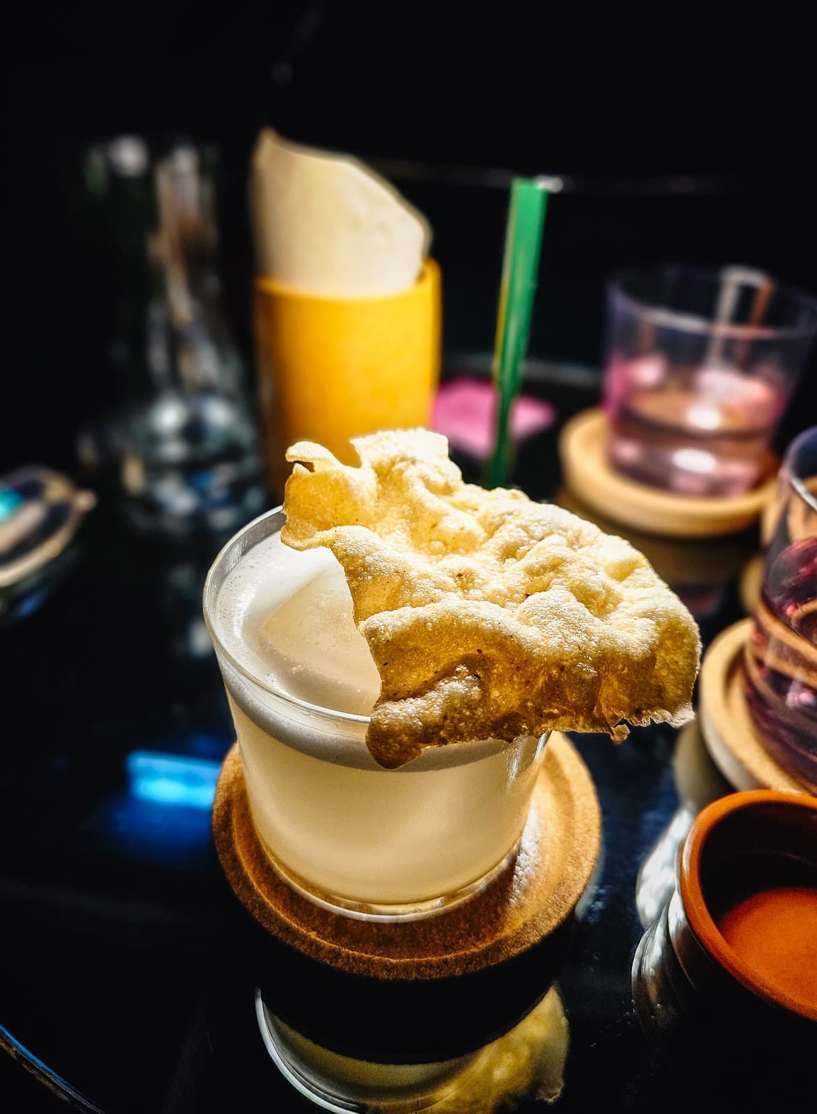 Cocktail with a crispy garnish on a glass table at a bar in Lisboa