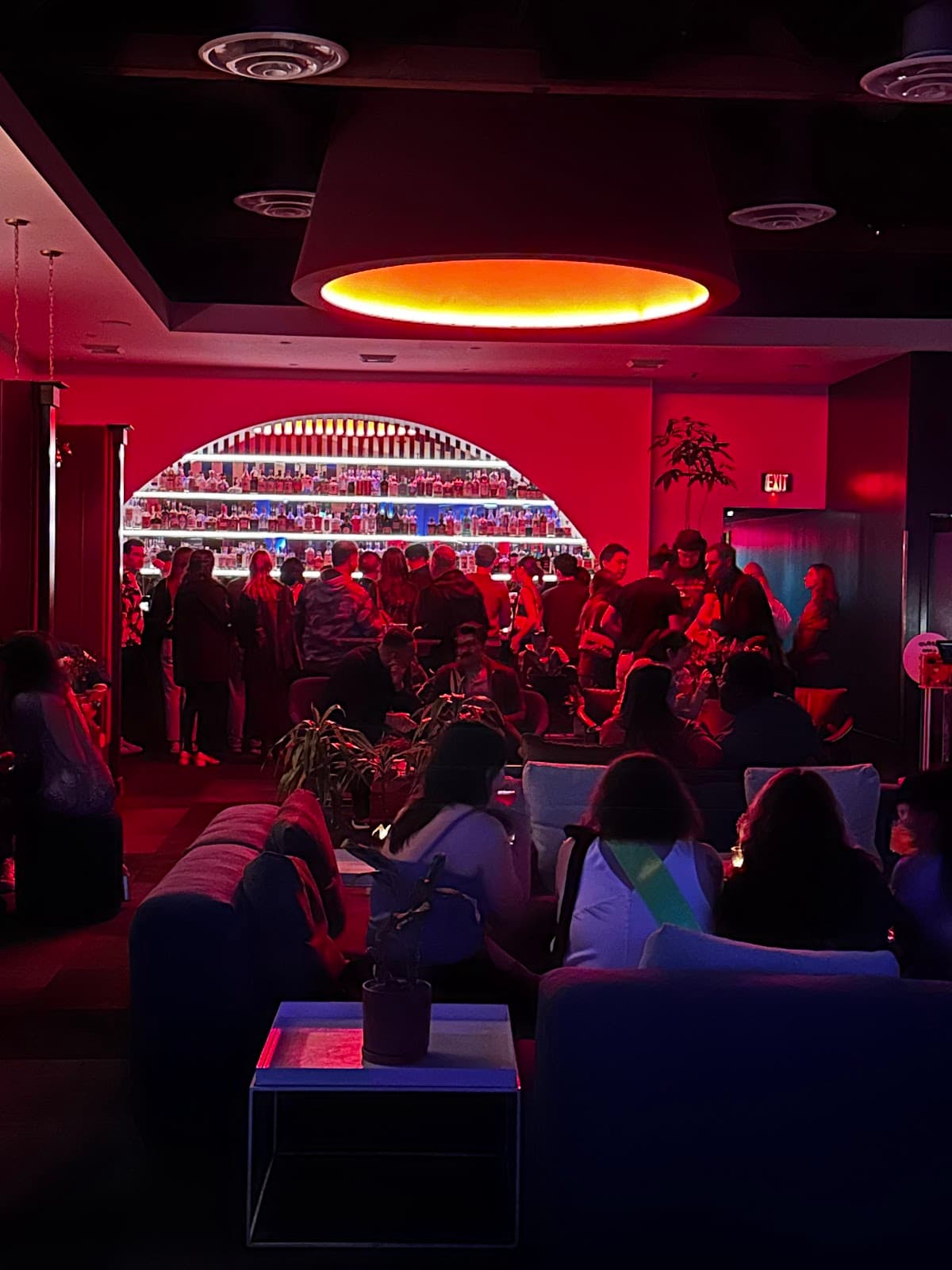Dimly lit cocktail bar with vibrant red lighting and patrons lounging in San Francisco
