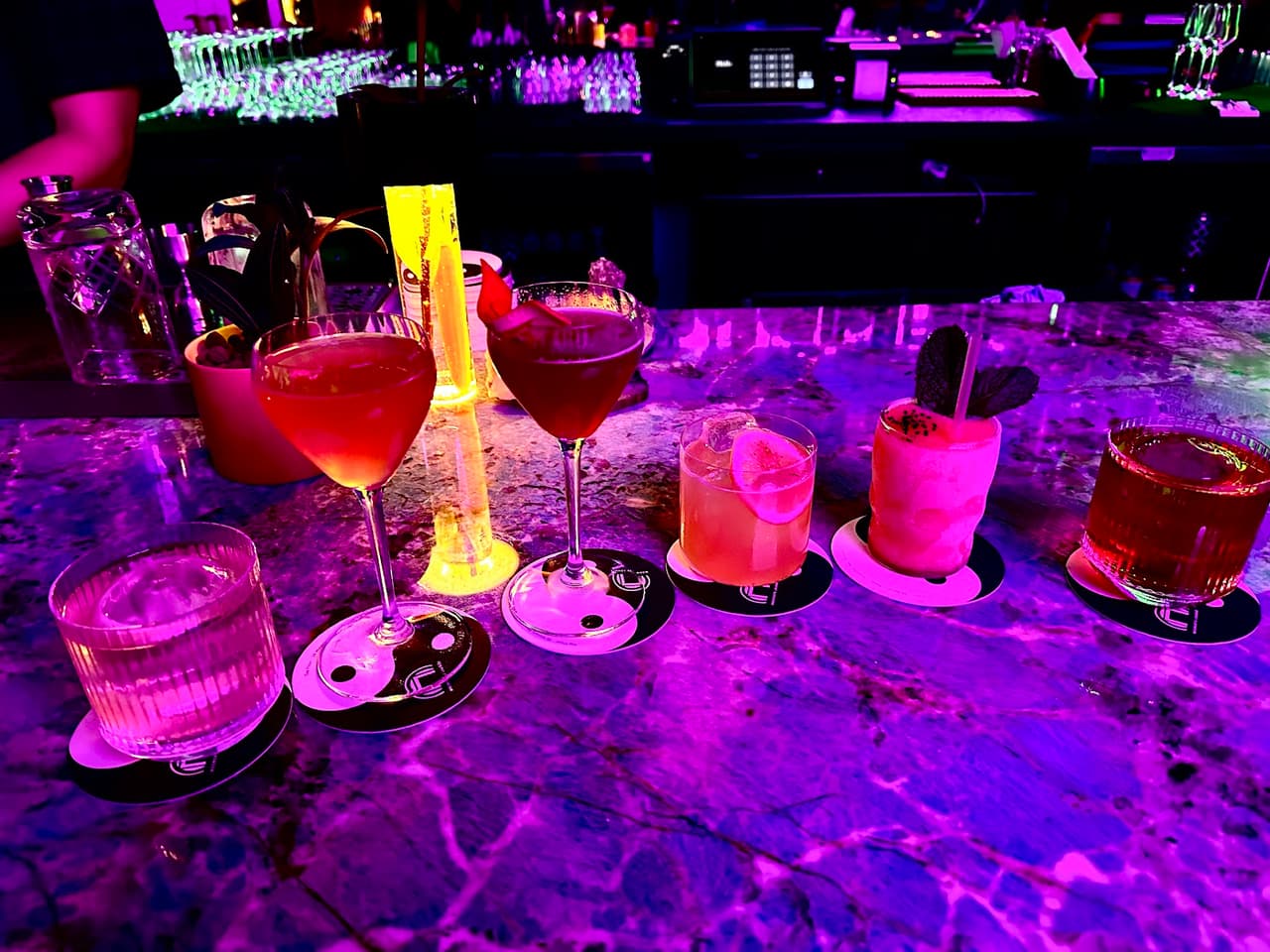 Colorful cocktails on a marble bar under neon lighting in San Francisco