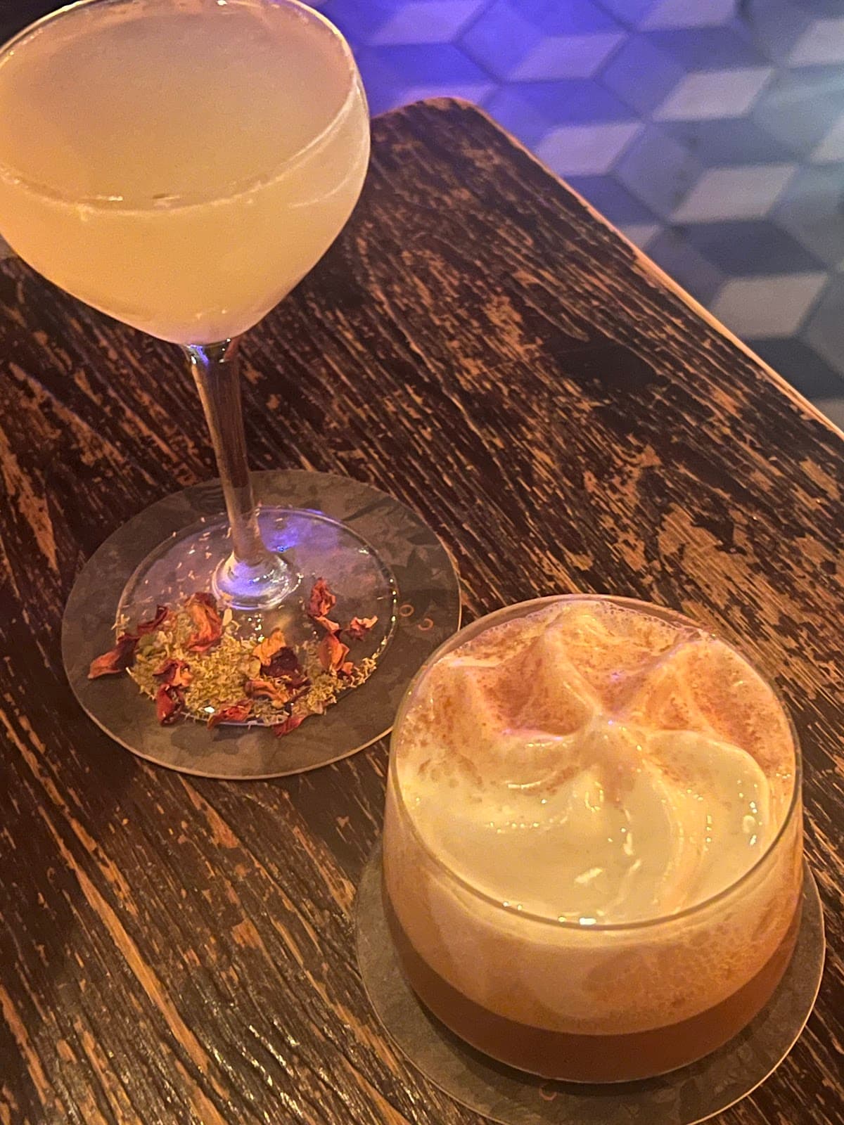 Two cocktails on a rustic wooden table with a tile floor background. in Toronto