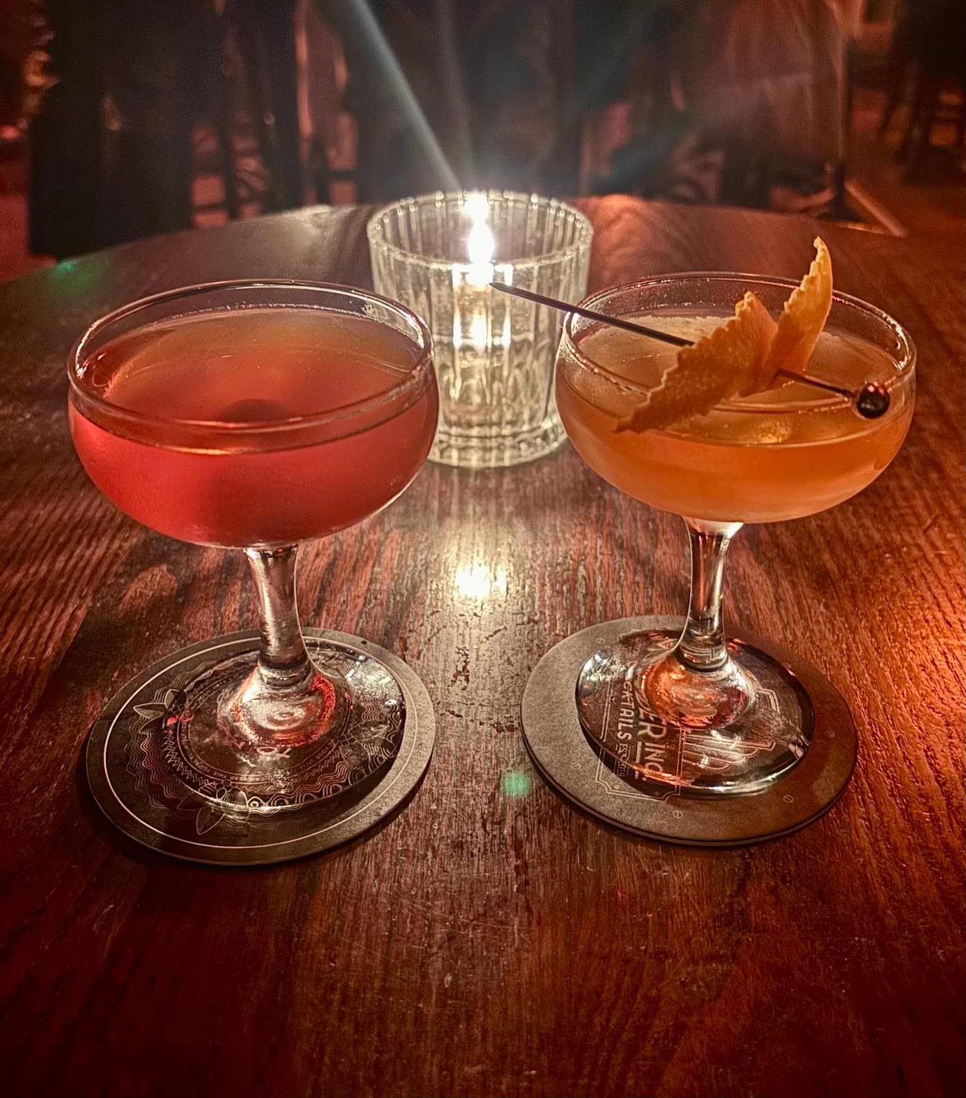 Two cocktails on a wooden table with a candle in the background in London