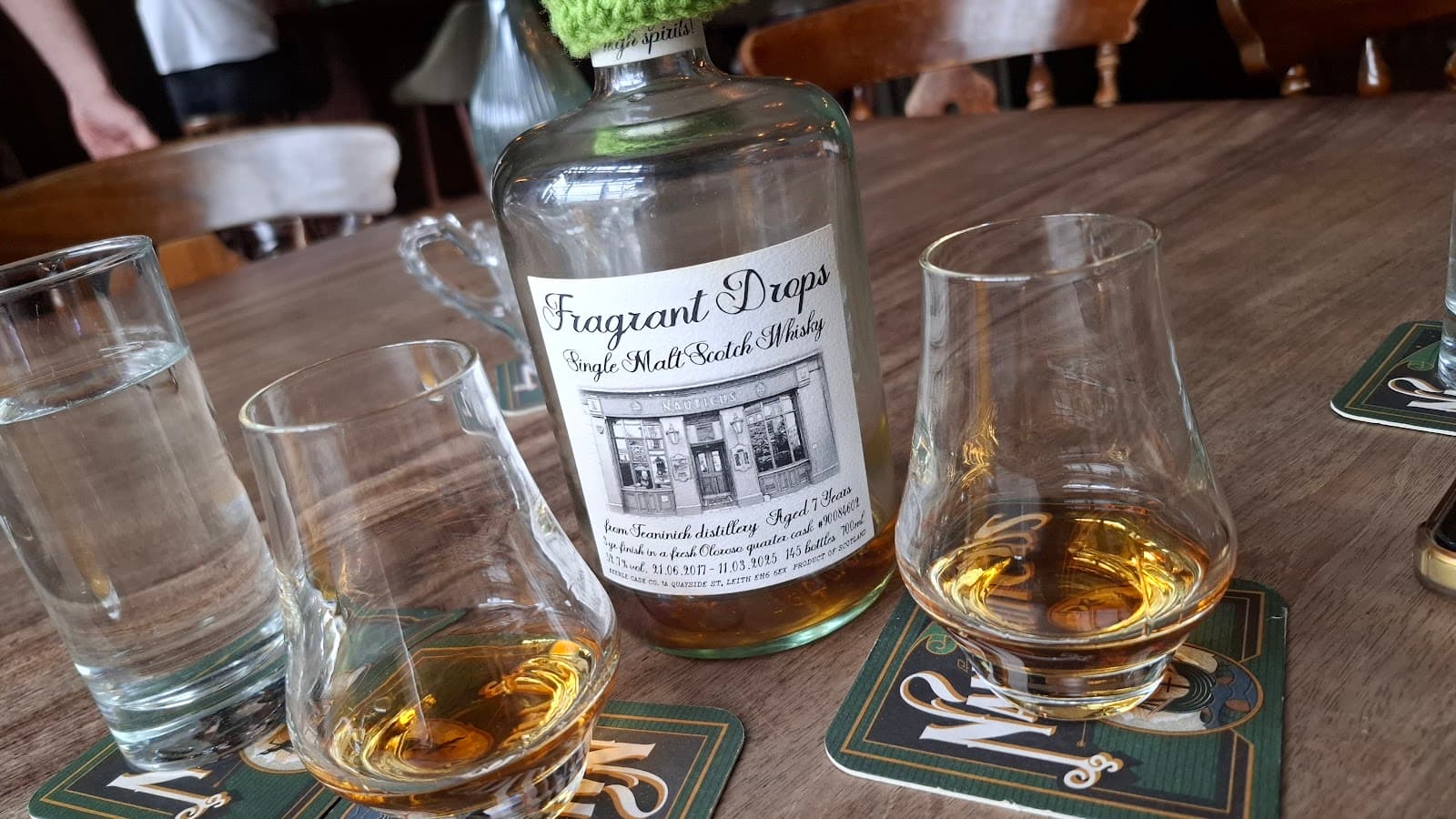 Whiskey bottle and glasses on a wooden table in a bar setting in Edinburgh