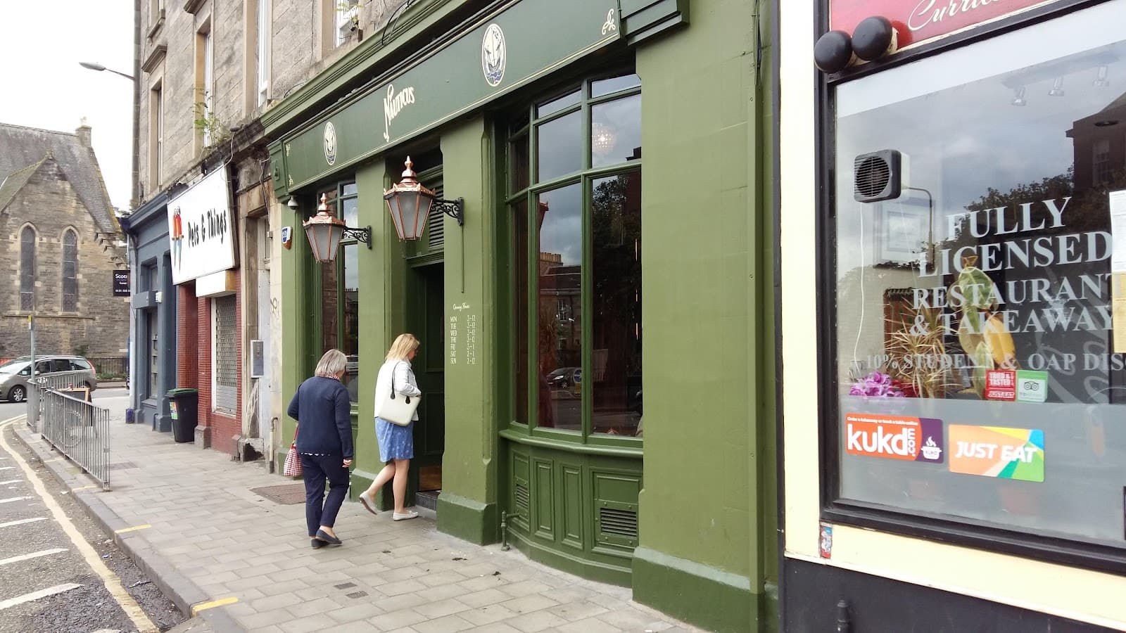 Exterior of a green-painted cocktail bar with people entering in Edinburgh