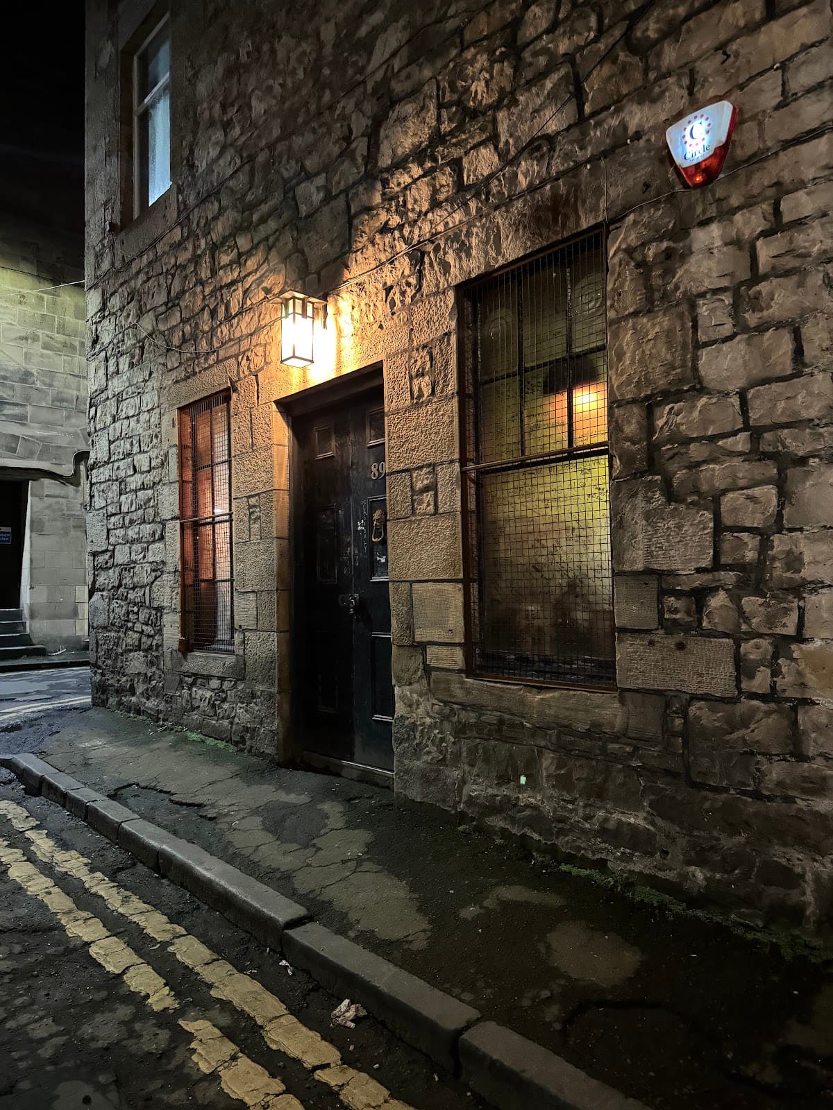 Exterior view of stone building with a warmly lit door at night in Edinburgh