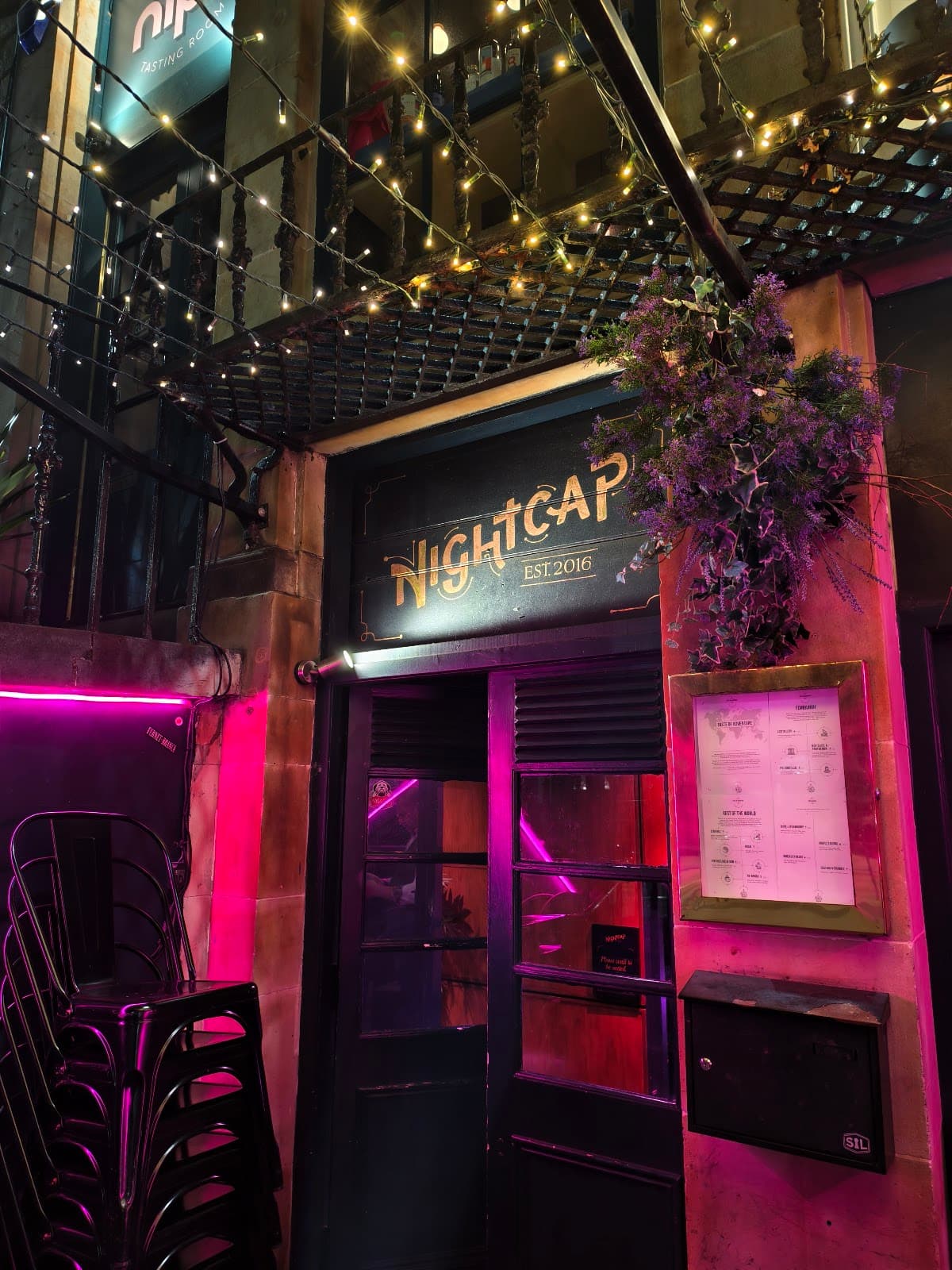Entrance of Nightcap bar with string lights and menu on the wall.