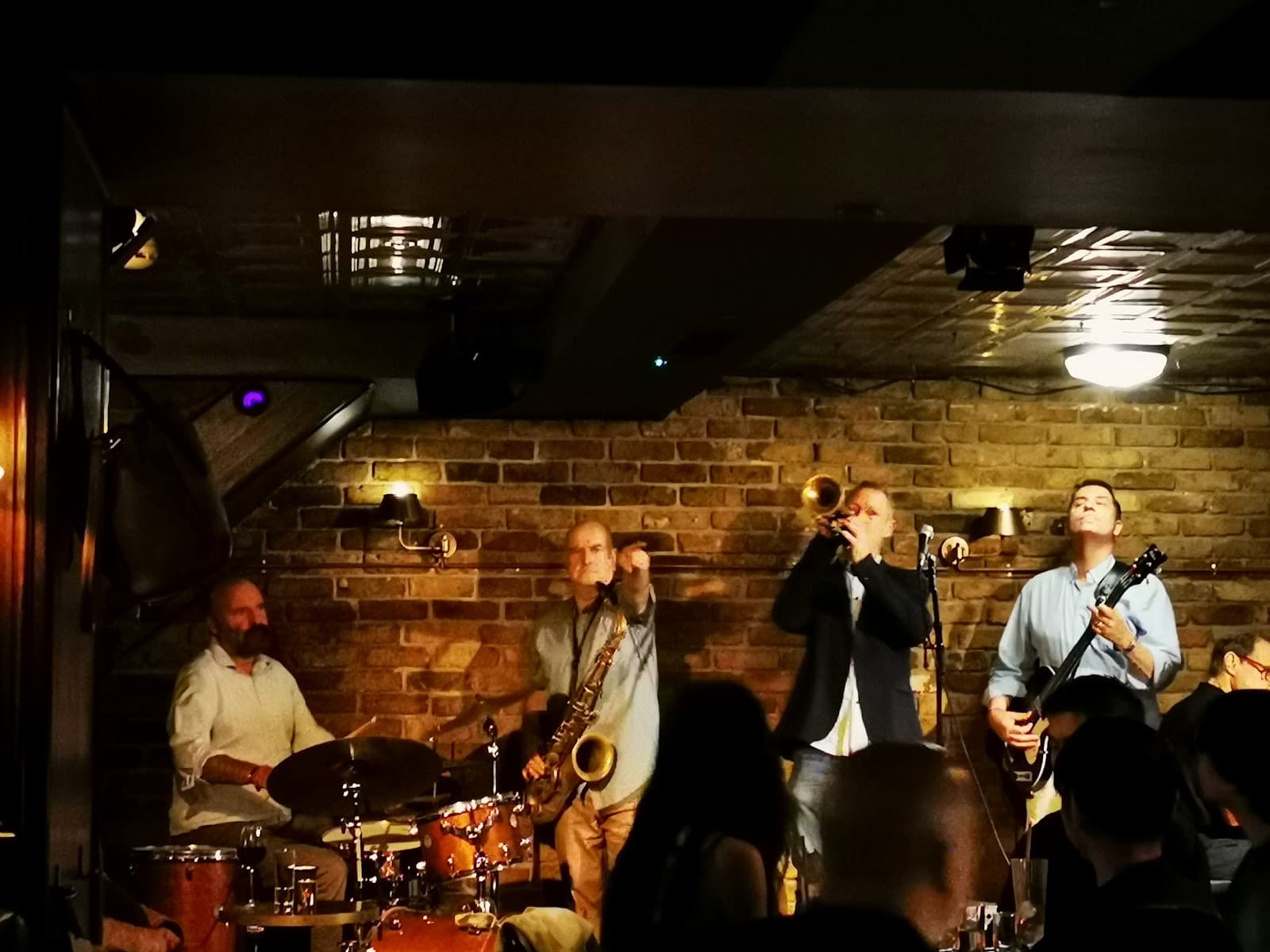 Live band performing in a dimly lit bar with exposed brick walls in London
