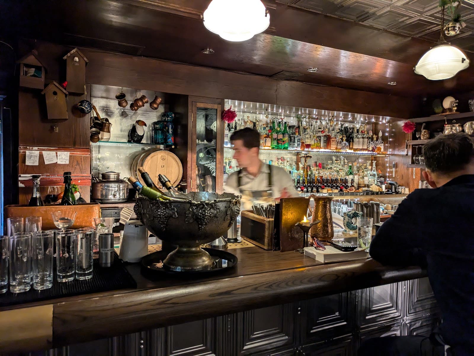 Cozy bar interior with a bartender and an array of bottles on display in London