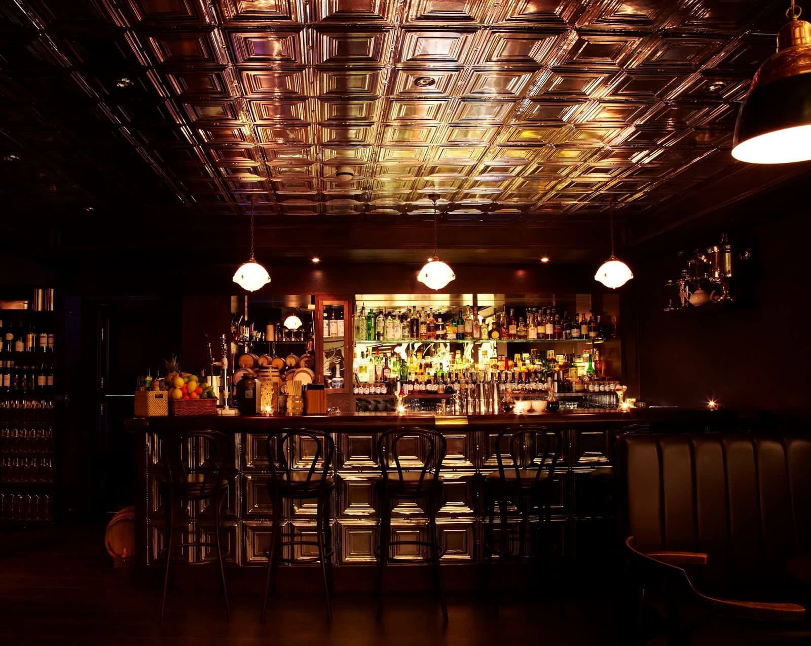 Dimly lit bar with ornate ceiling and stocked shelves