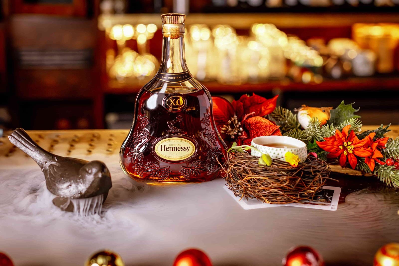 Hennessy XO bottle with festive decorations and a fog effect on bar counter in London