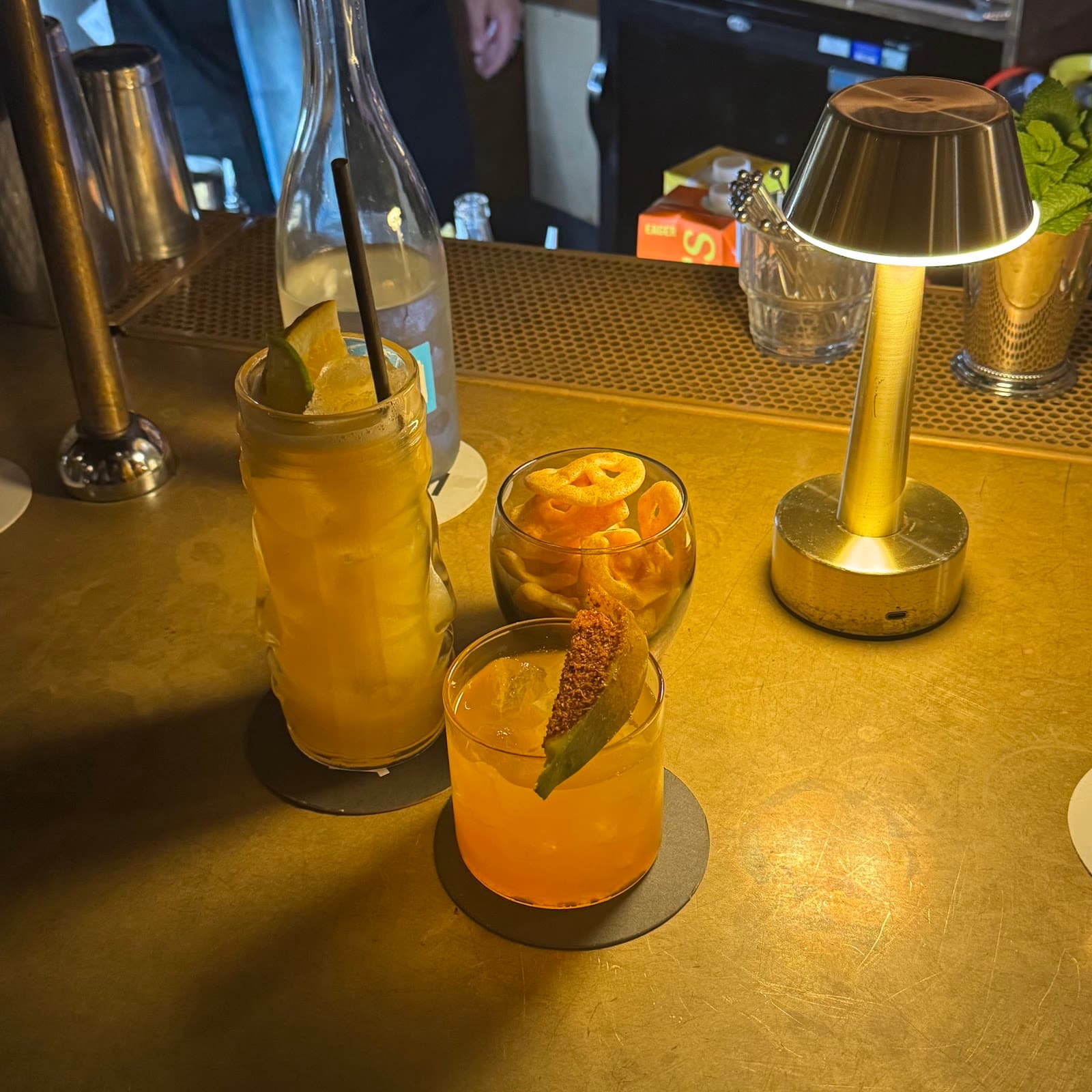 Bar counter with cocktails, snacks, and a small lamp in London