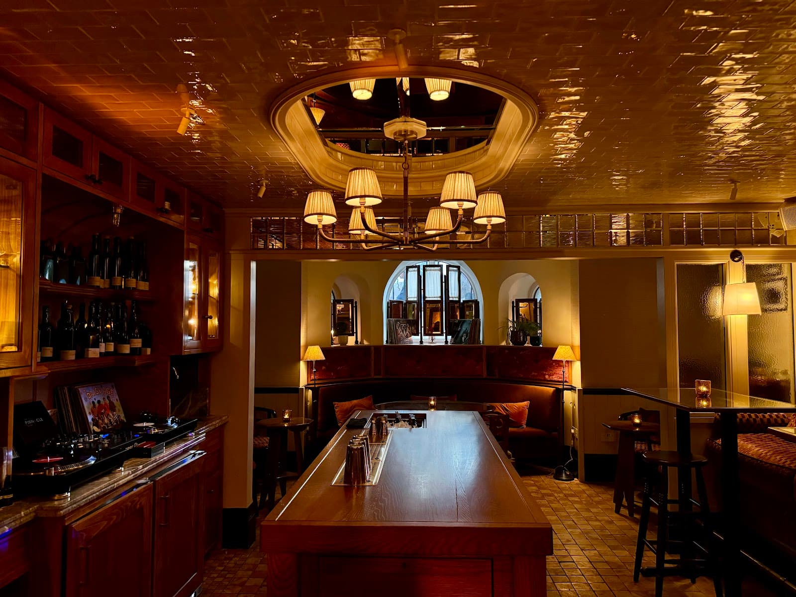 Warmly lit bar interior with chandeliers and wooden furnishings