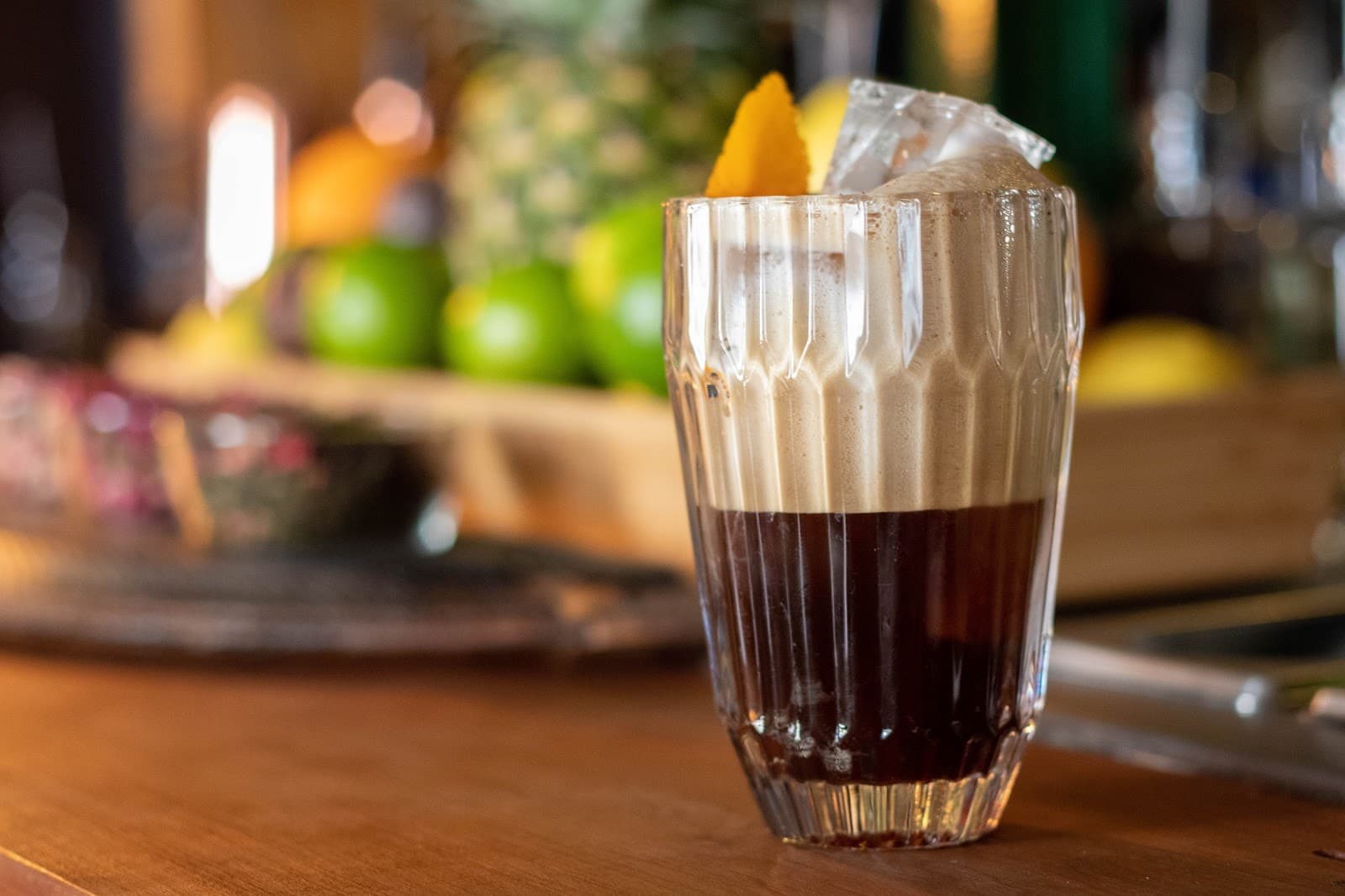 Close-up of a coffee cocktail with citrus garnish on a wooden bar counter in Lisboa