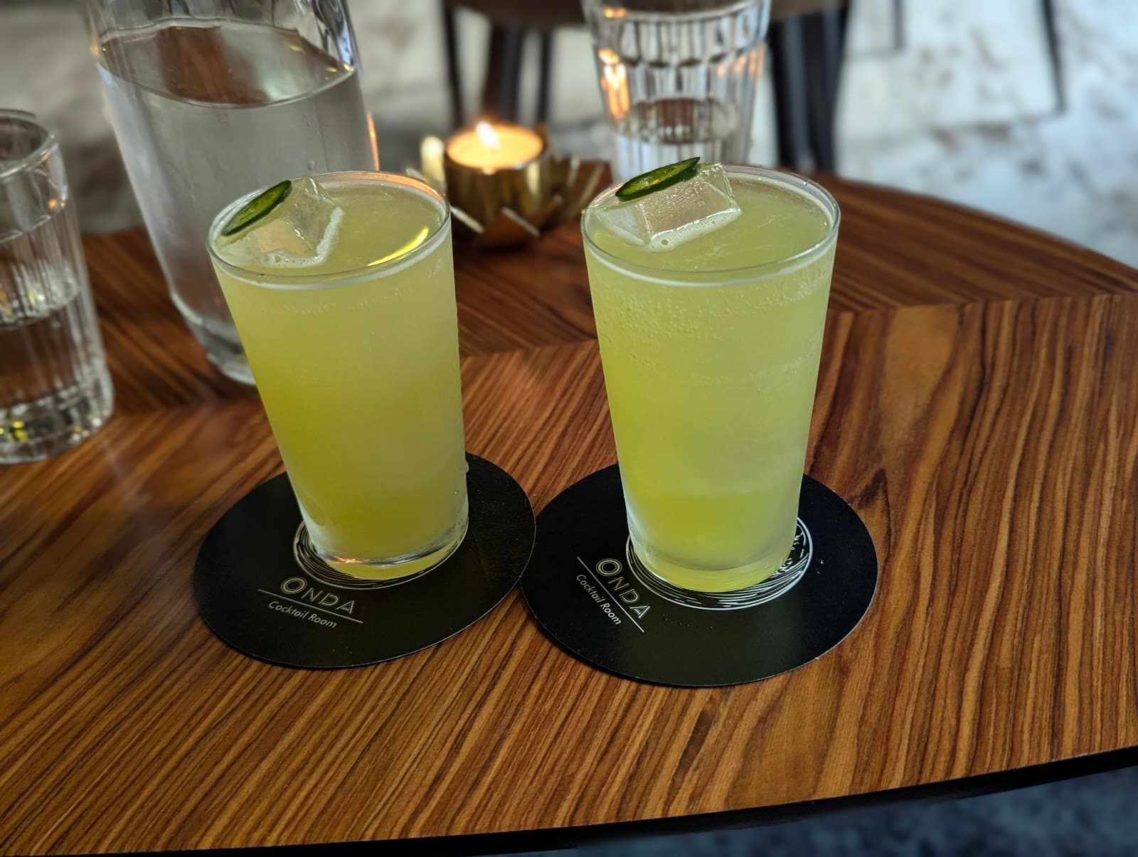 Two yellow cocktails with lime slices on a wooden table at Onda Cocktail Room in Lisboa