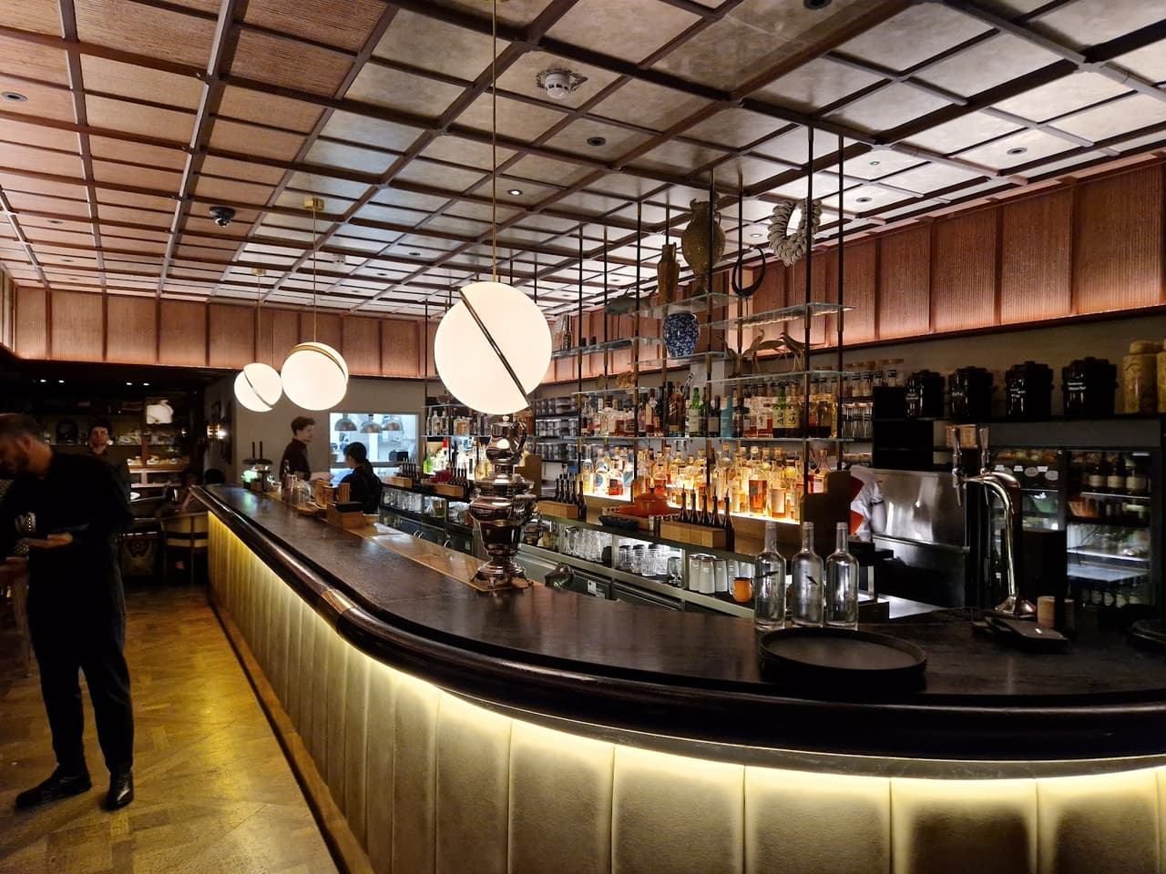 Elegant bar with warm lighting and stocked shelves at a cocktail venue in London