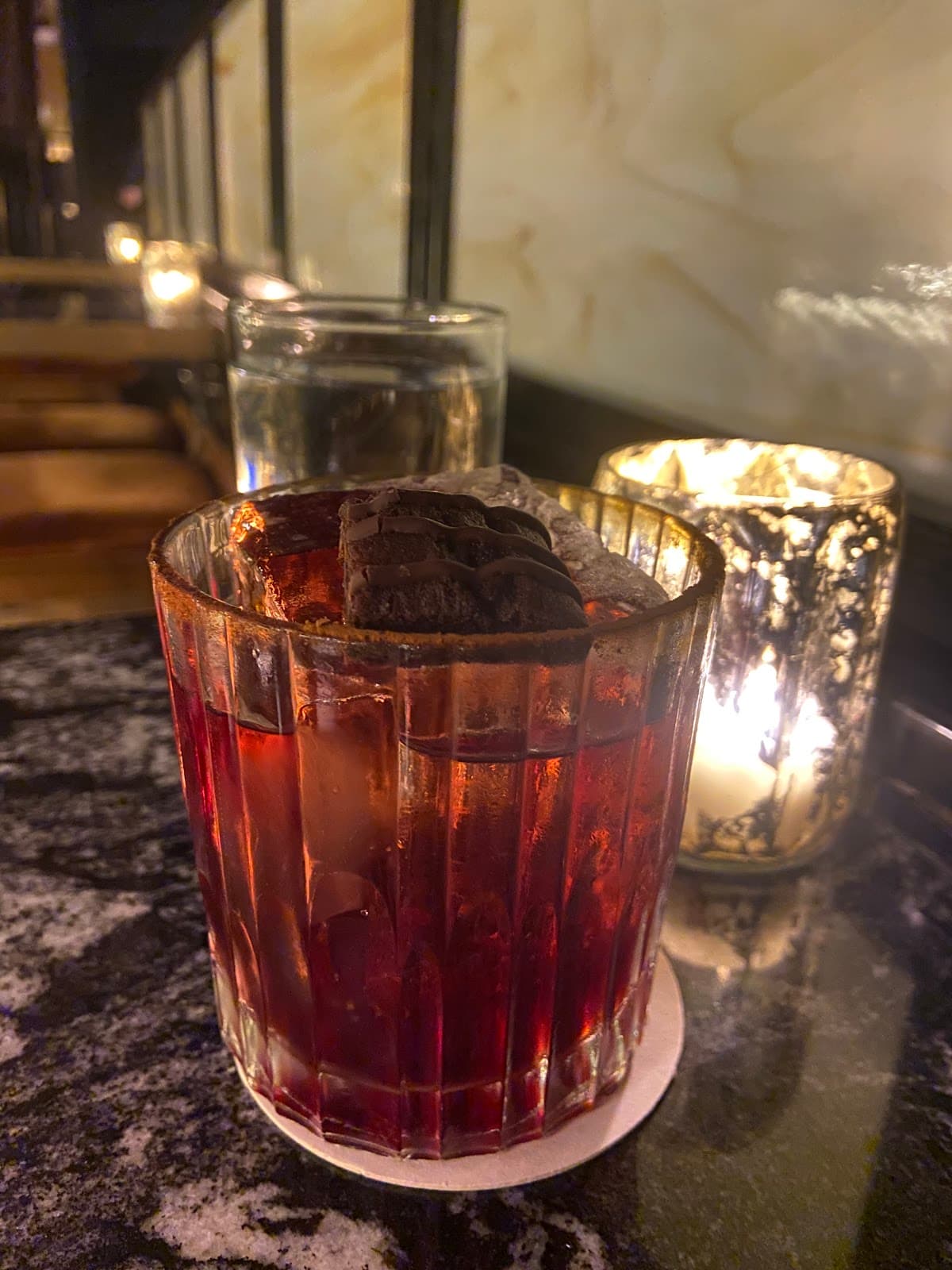 Garnished cocktail in a dimly lit bar setting with candles in London