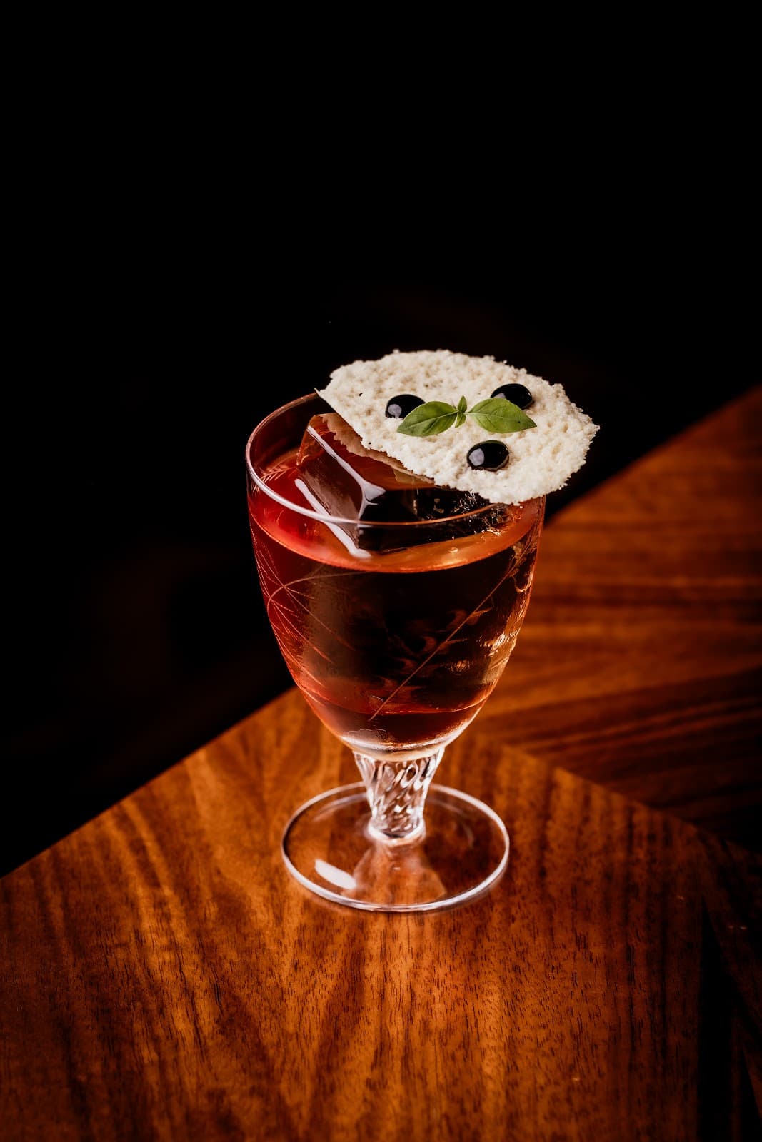 Elegant cocktail on a wooden table with garnish and dark background in London