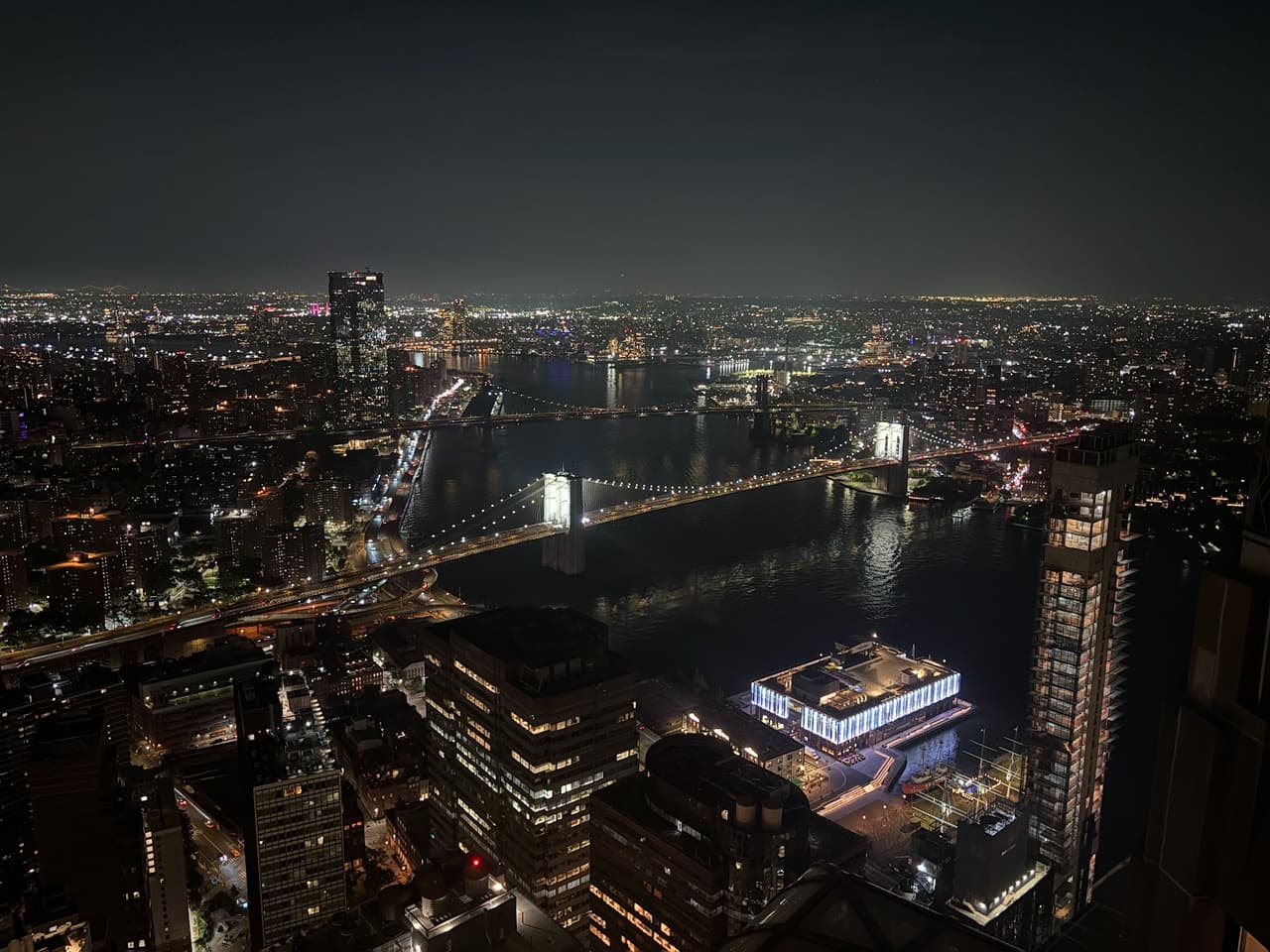 Night cityscape view featuring a lit bridge and surrounding skyline in New York