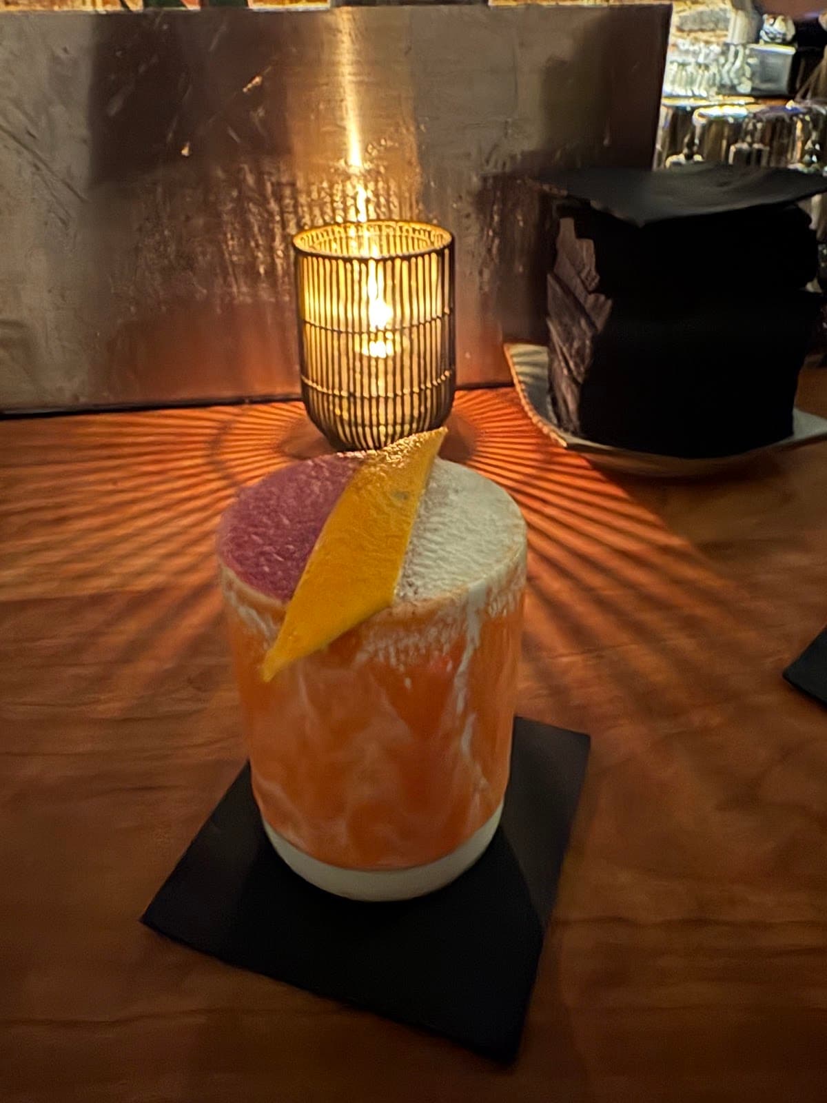 Cocktail with orange peel garnish on a bar counter with candlelight in San Francisco