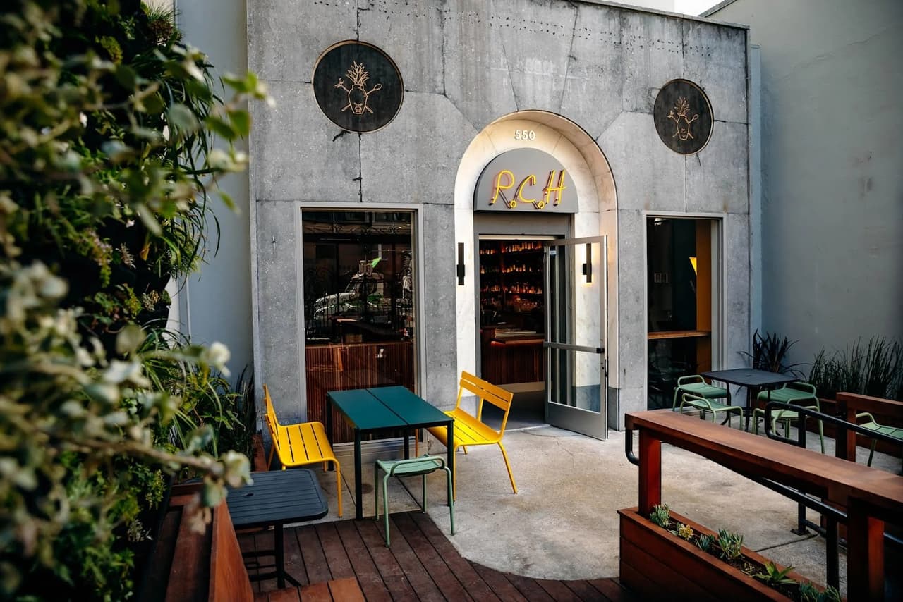 Stylish bar entrance with yellow neon sign and outdoor seating in San Francisco