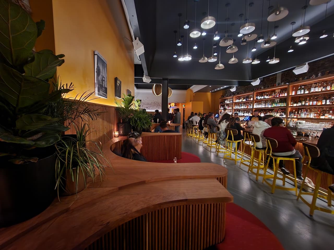 Stylish bar interior with vibrant yellow stools and a ceiling of modern lights
