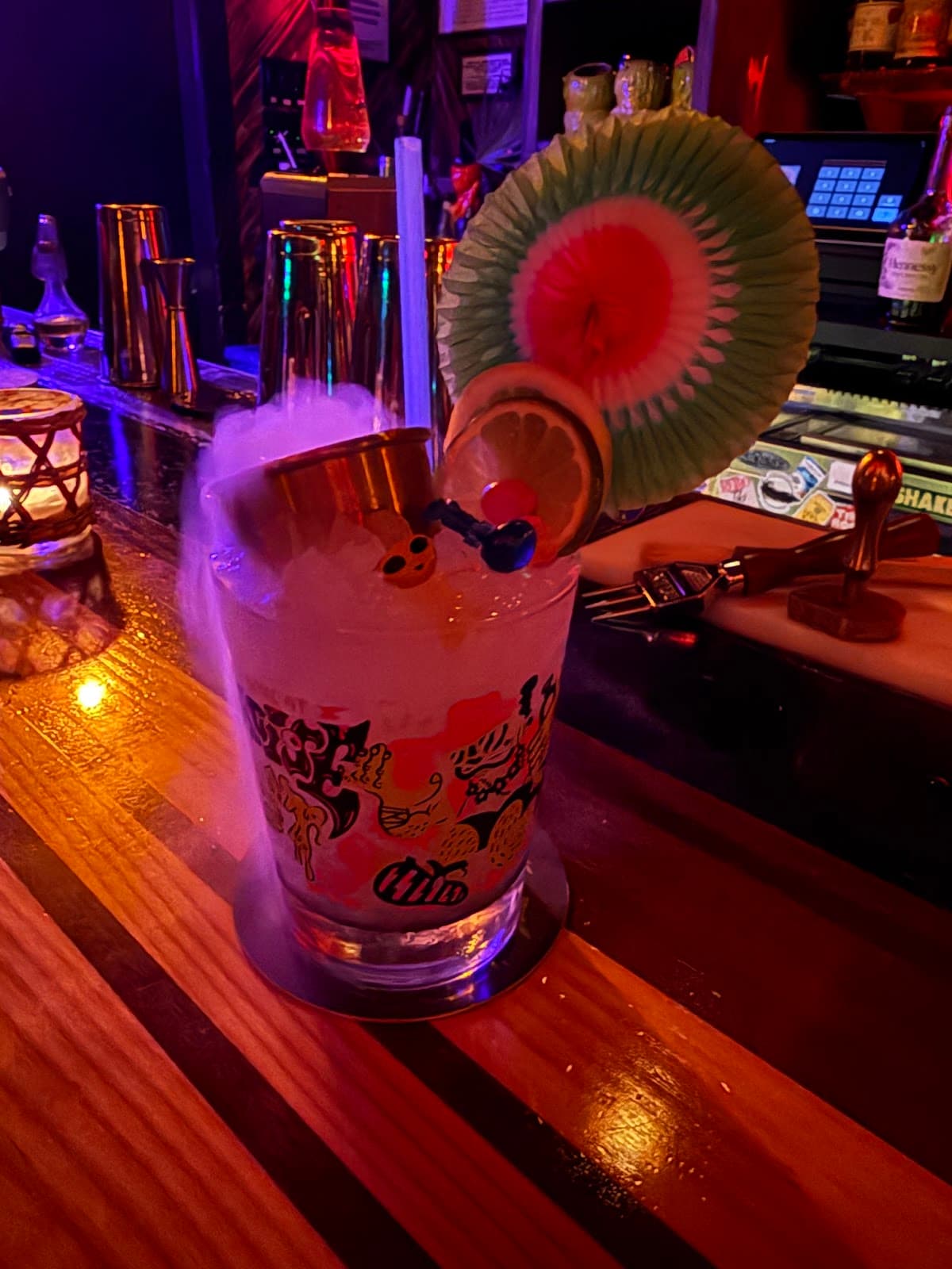 Colorful cocktail on bar counter with decorations and dry ice smoke in New York