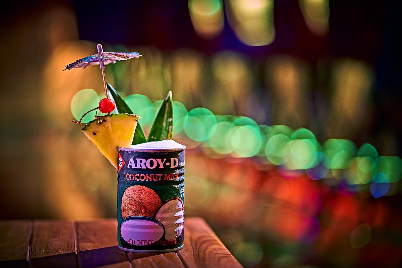 Colorful cocktail in a coconut milk can with garnish on a wooden table in New York