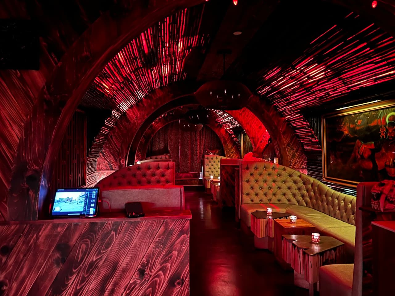 Stylish interior with red lighting, tufted booths, and arches