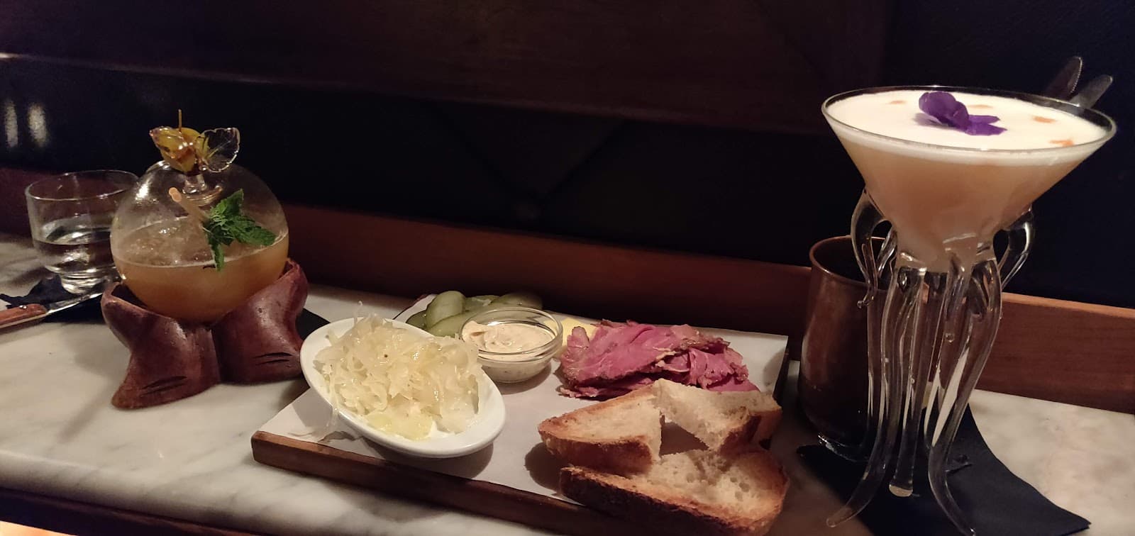 Artistic cocktails with appetizers on marble counter in dim light in Barcelona