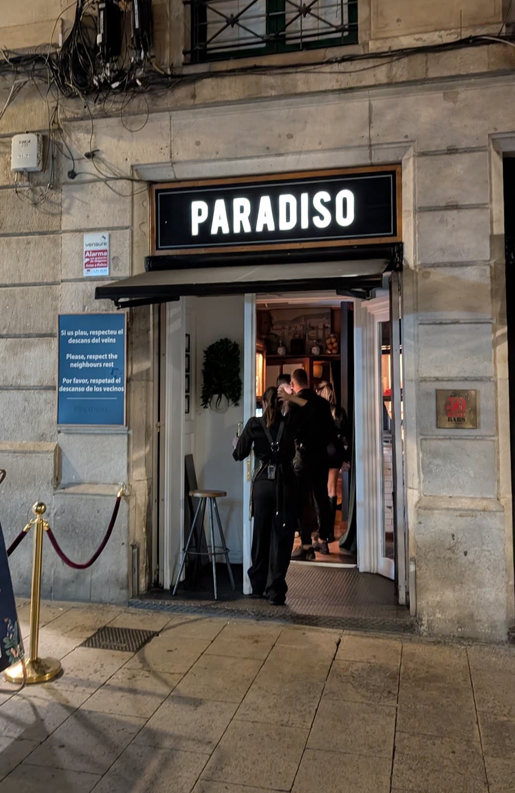 Entrance of Paradiso bar with people entering on a cobblestone street in Barcelona