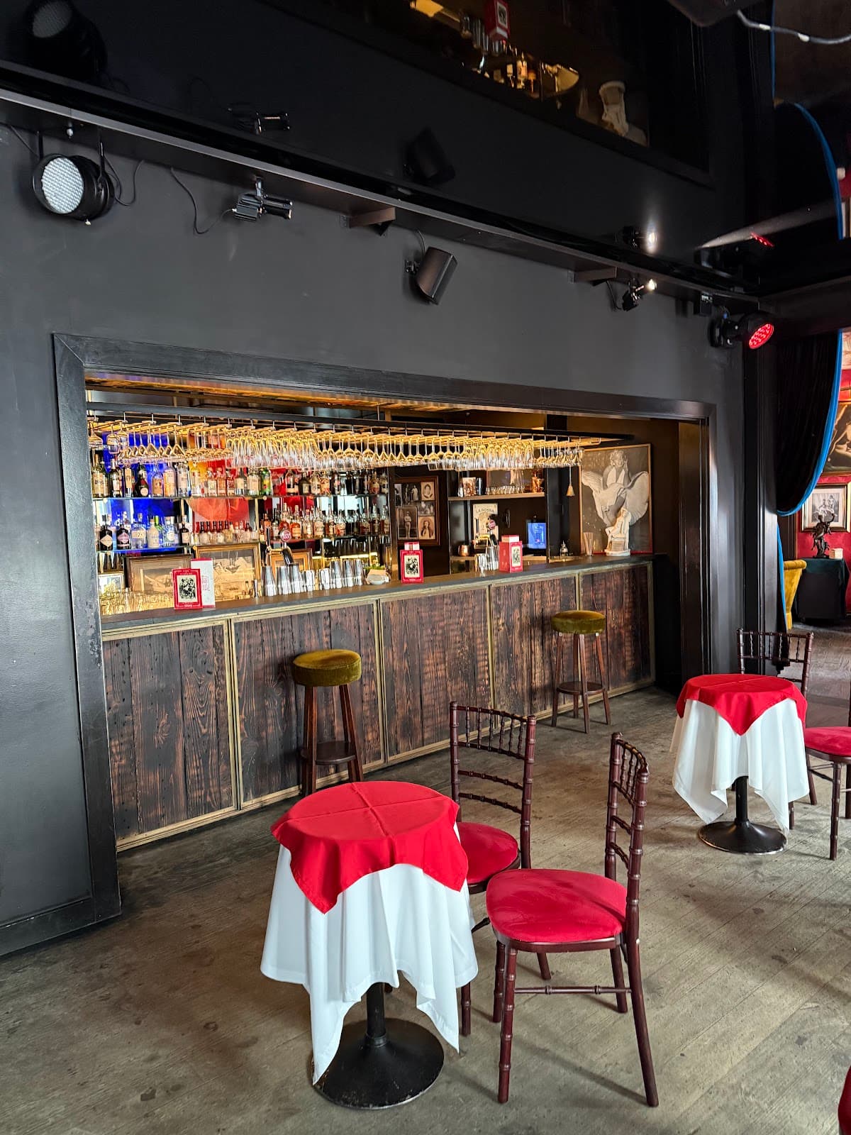 Bar interior with stools, tables, and exposed bottles on shelves in Lisboa