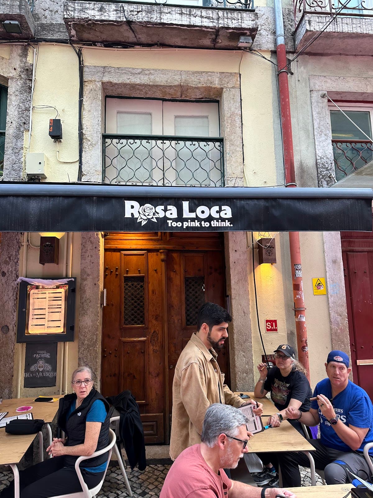 Exterior view of Rosa Loca with outdoor seating and patrons in Lisboa