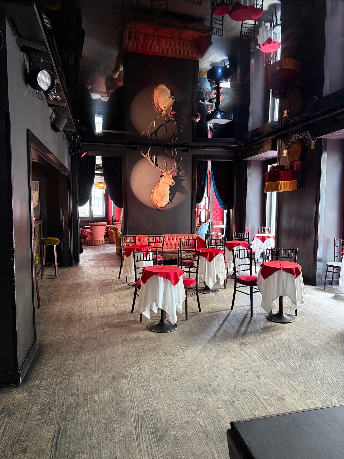 Interior with red and white table settings and wall-mounted deer heads in Lisboa