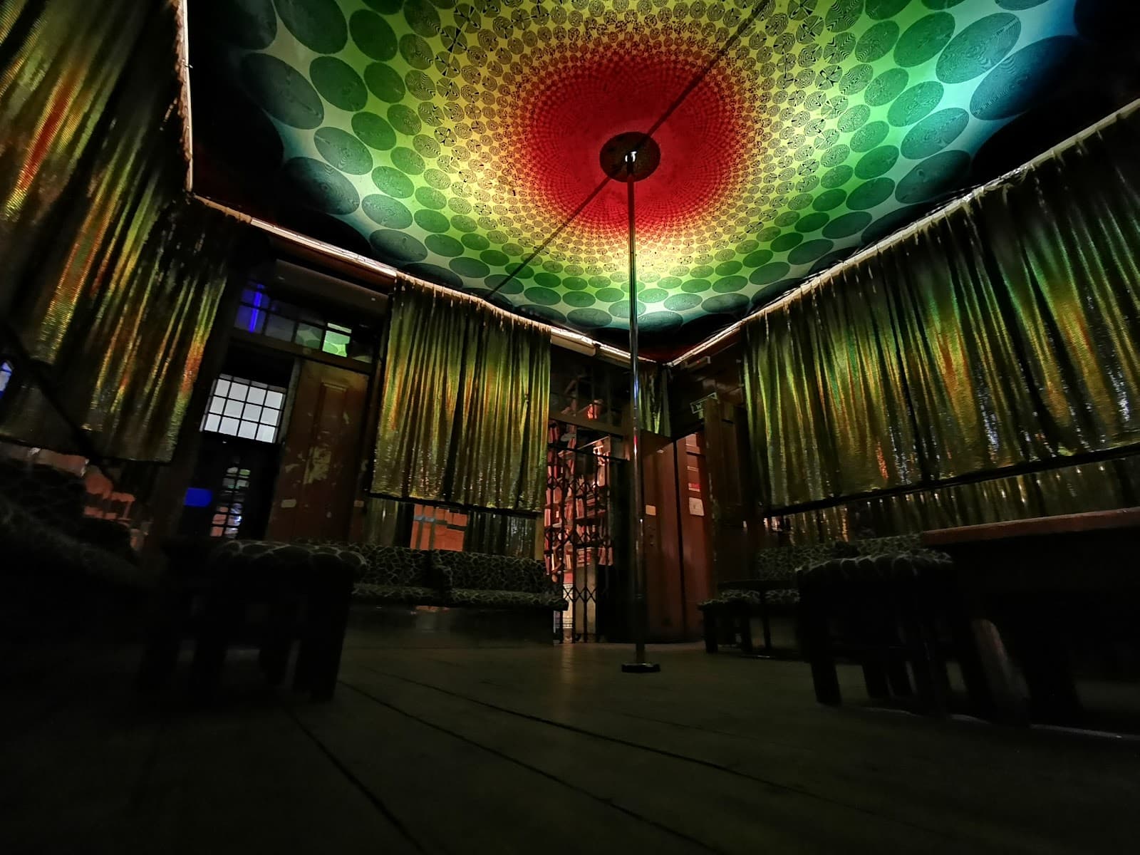 Colorful ceiling with patterned curtains in dimly lit bar interior in Lisboa