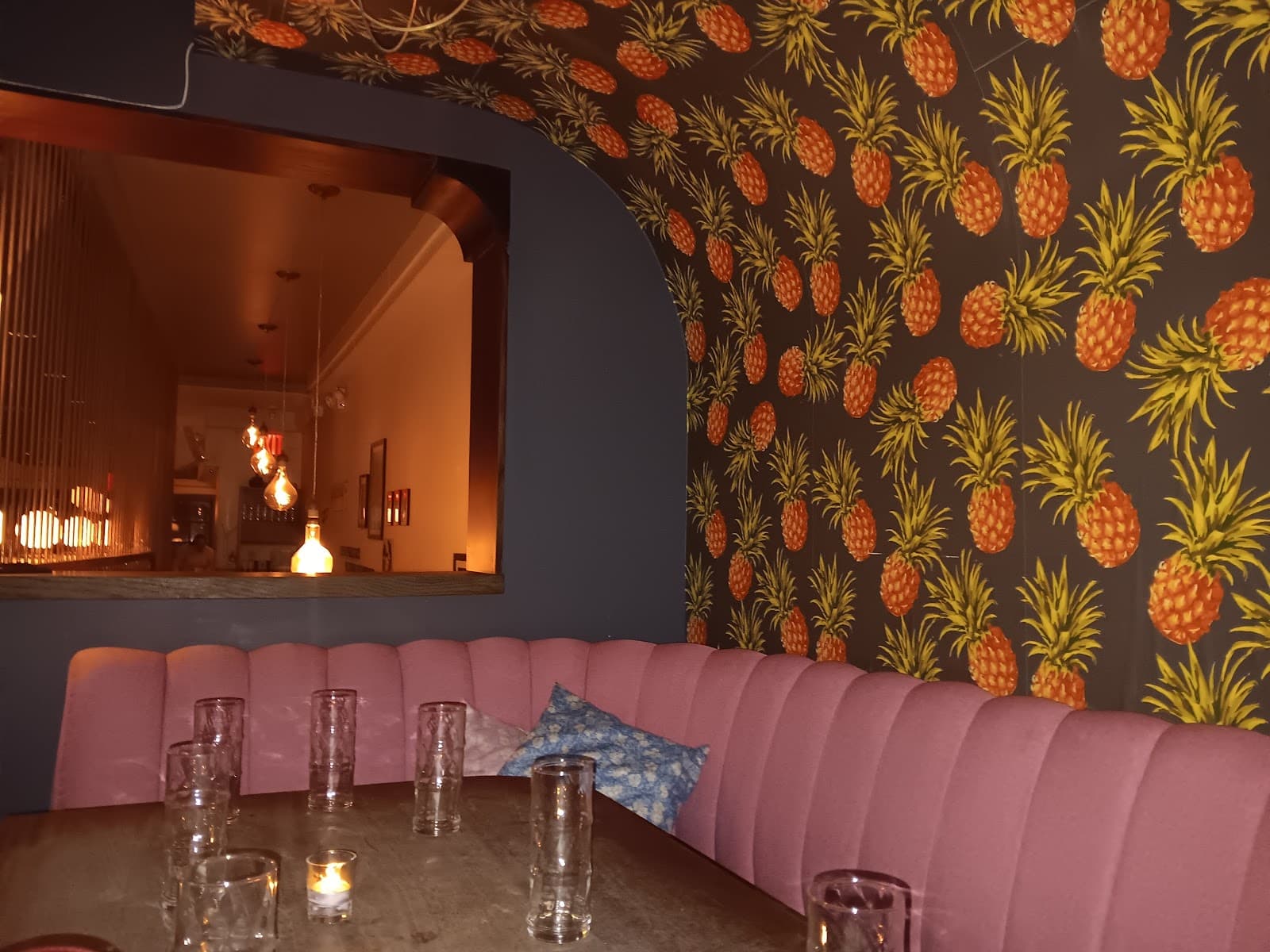 Pineapple wallpaper interior with pink seating and candles in New York