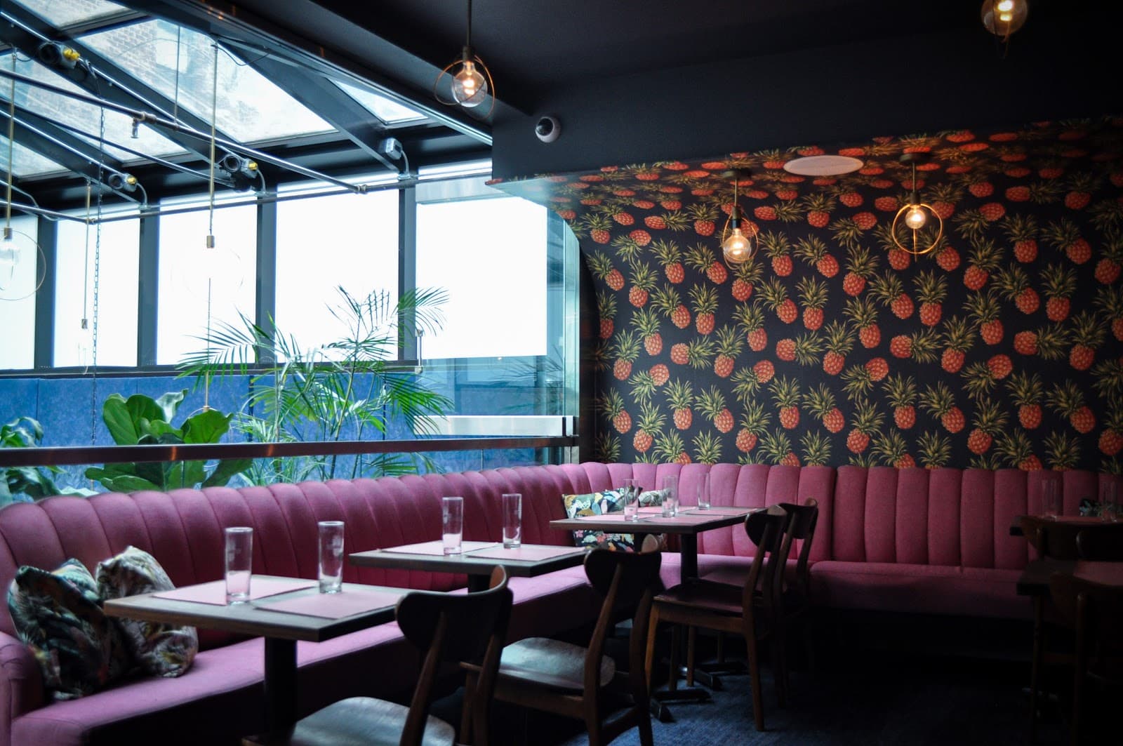 Interior with pink seating and pineapple wallpaper in cocktail bar