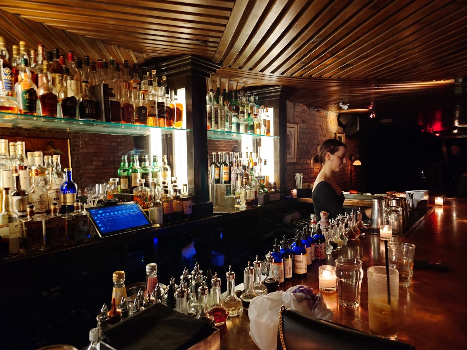 Bartender at a stocked wooden bar with warm lighting in New York