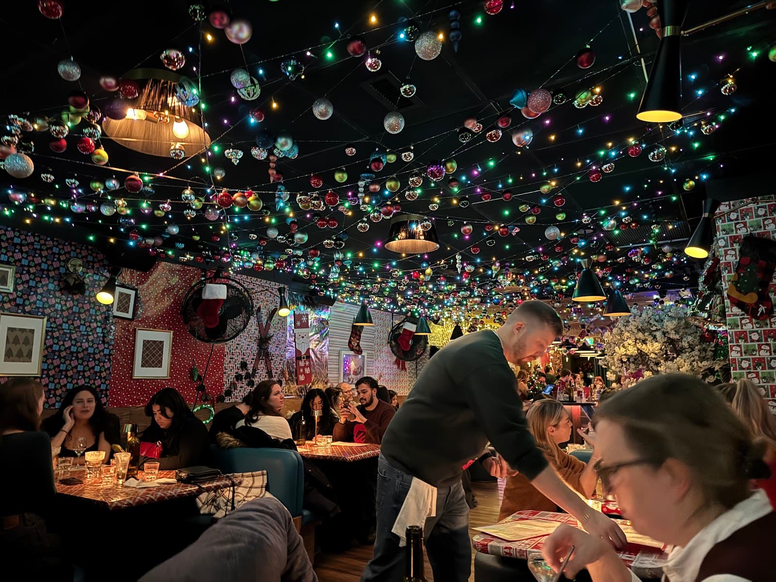 Festive bar interior with string lights and patrons at tables in Toronto