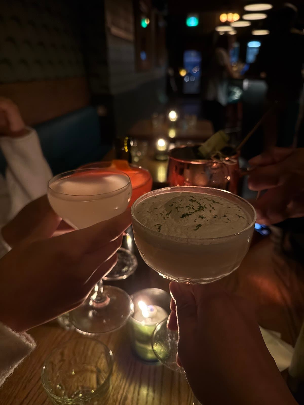 Dimly lit bar with cocktails and candles on a wooden table in Toronto