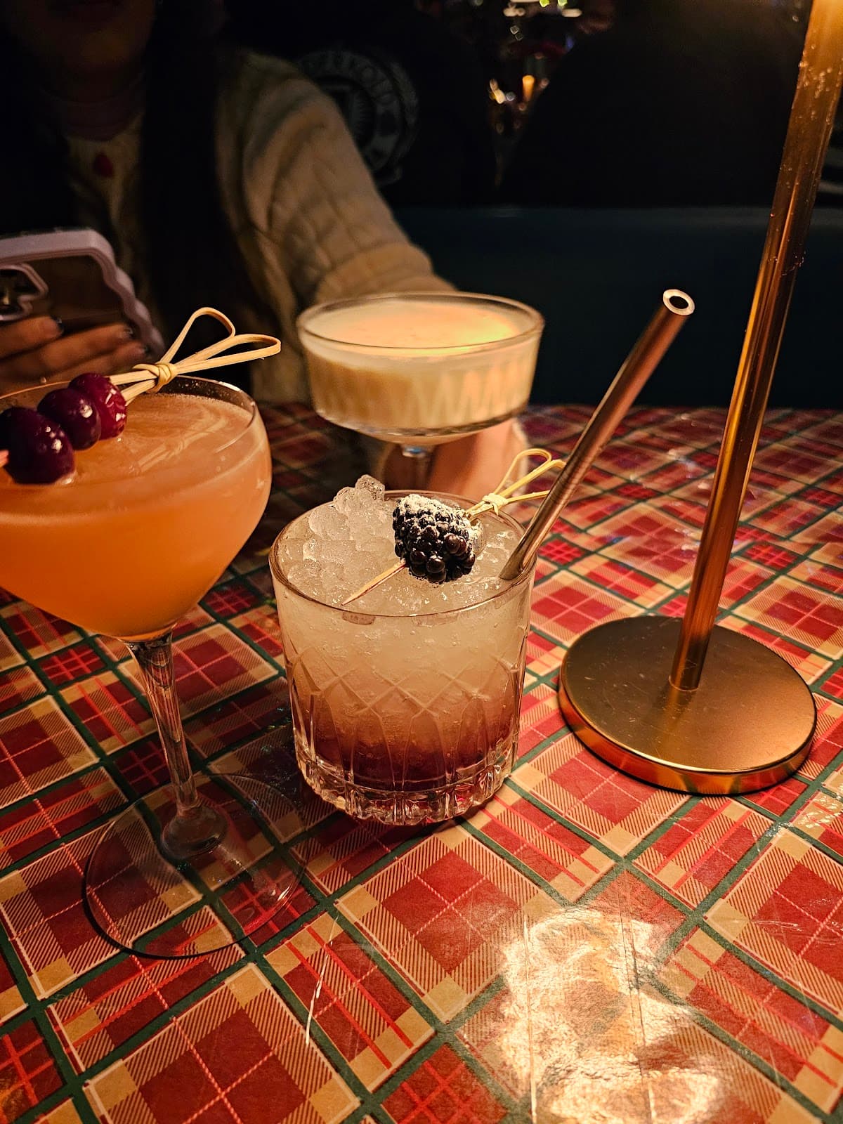 Three elegant cocktails with garnishes on a patterned table with warm lighting in Toronto