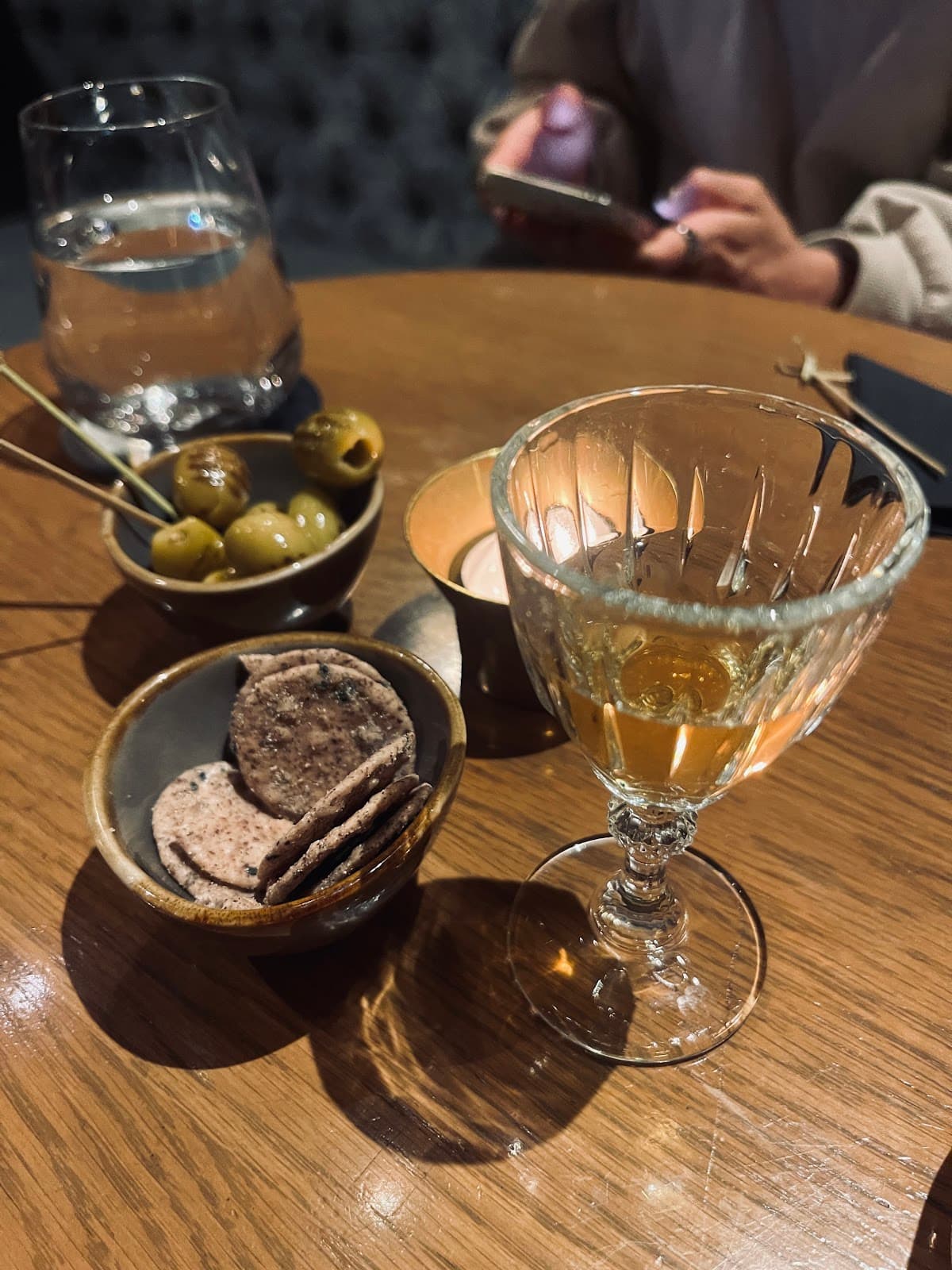 Cocktail glass with olives and crackers on a wooden table in London