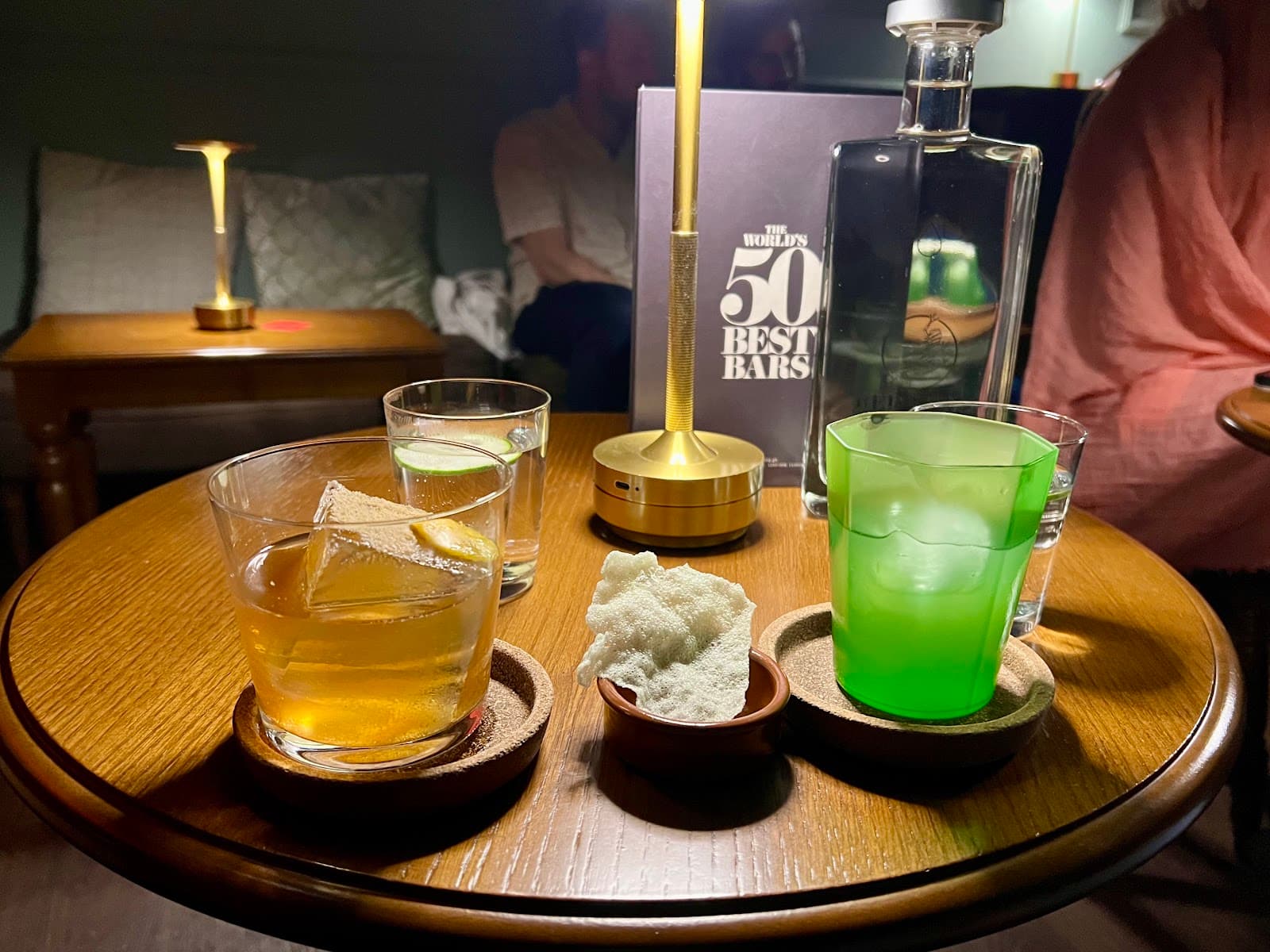 Table with cocktails, snacks, and 'World's 50 Best Bars' book. in Lisboa