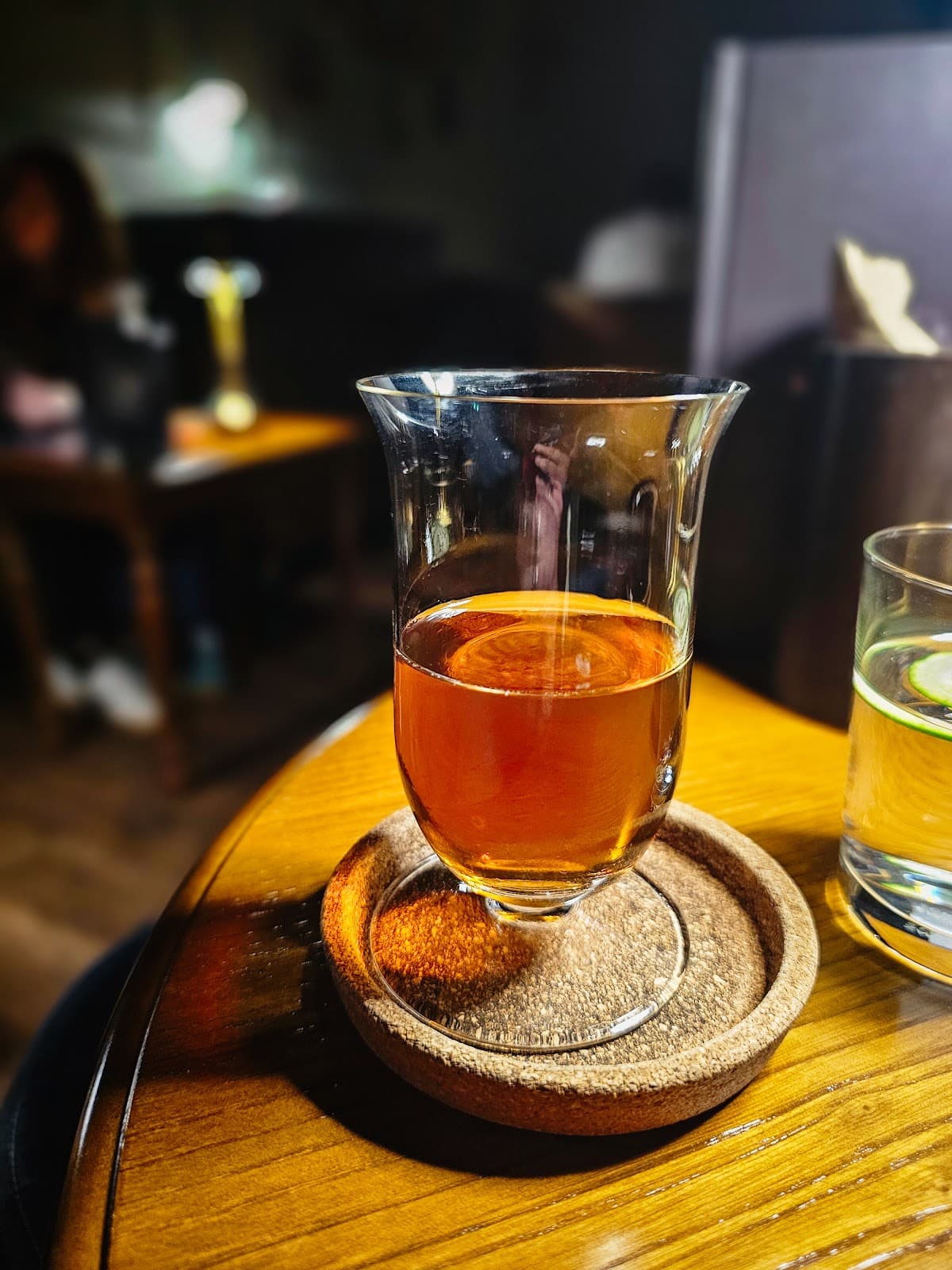 Close-up of cocktail in a glass on a wooden table in a dimly lit bar in Lisboa